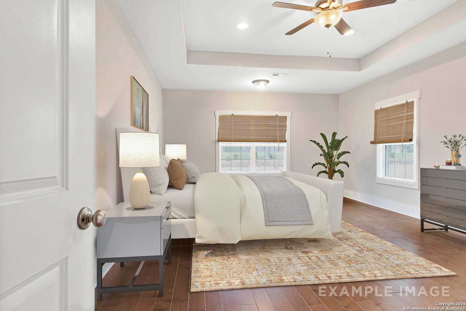Cozy master bedroom with king bed, ceiling fan, bamboo blinds, and hardwood floors in Davidson Homes The Lanier H, Ladera San Antonio