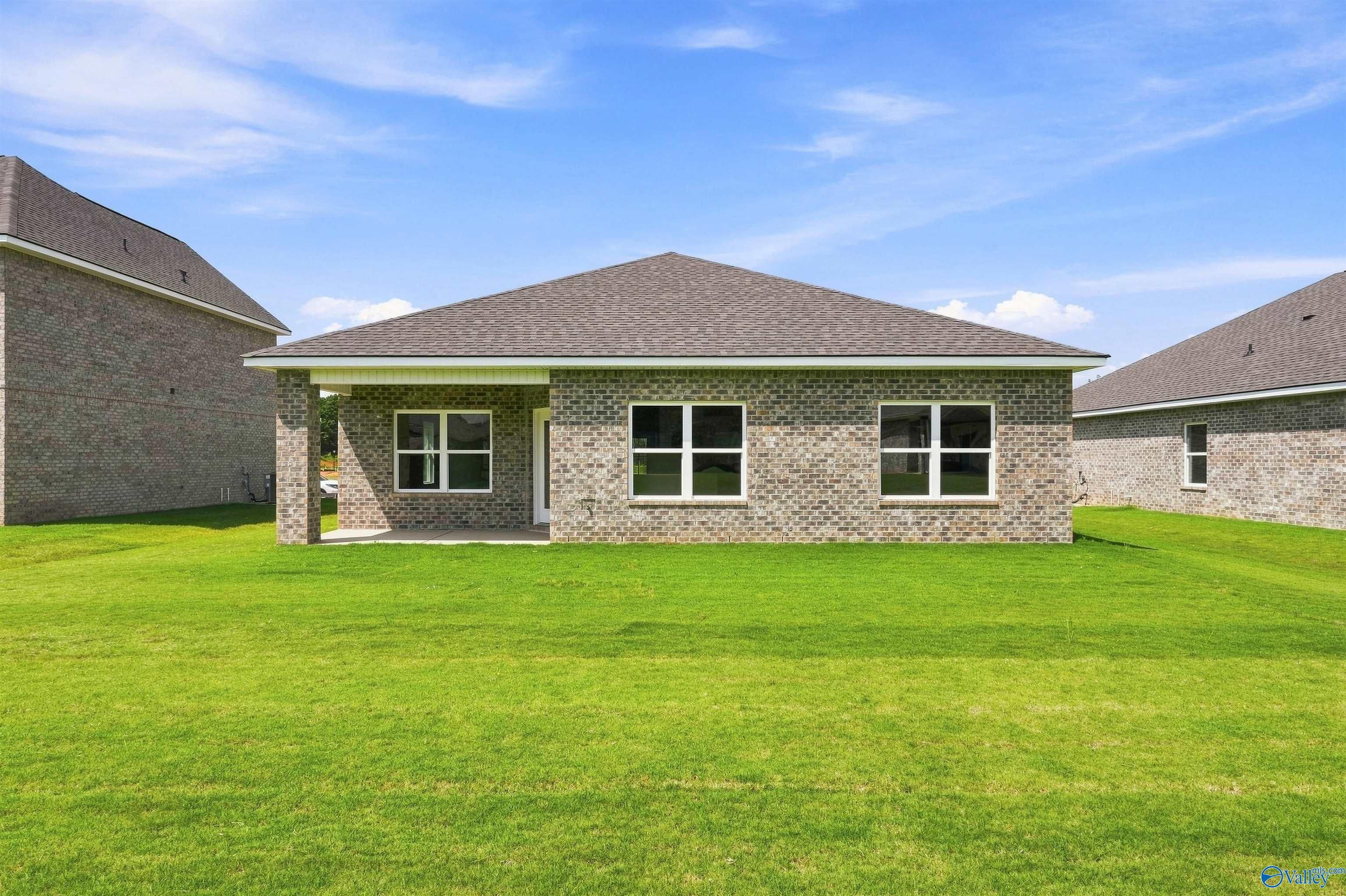 Rear exterior of brick single-story home with covered patio and large backyard in Wood Trail, Toney, Alabama by Davidson Homes
