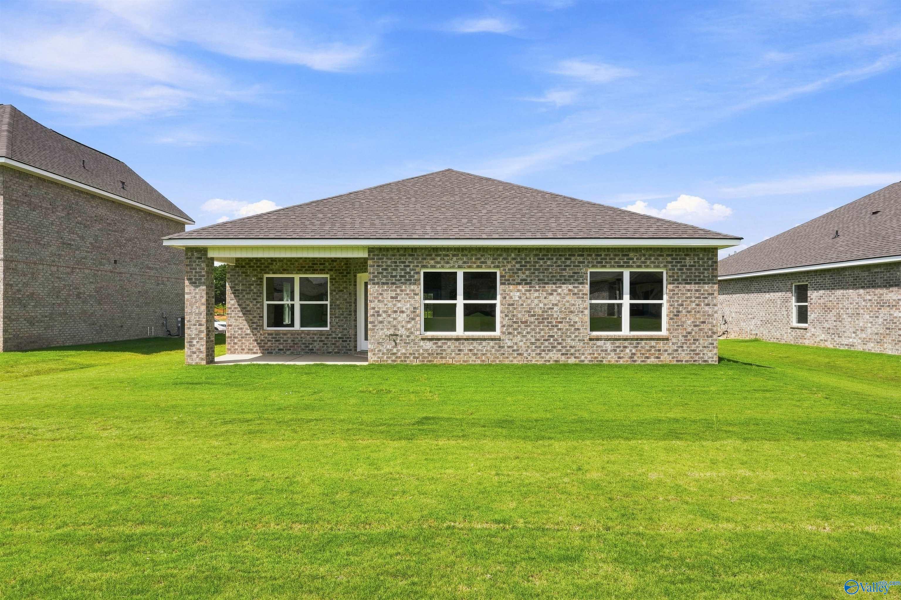 Rear exterior of brick single-story home with covered patio and large backyard in Wood Trail, Toney, Alabama by Davidson Homes