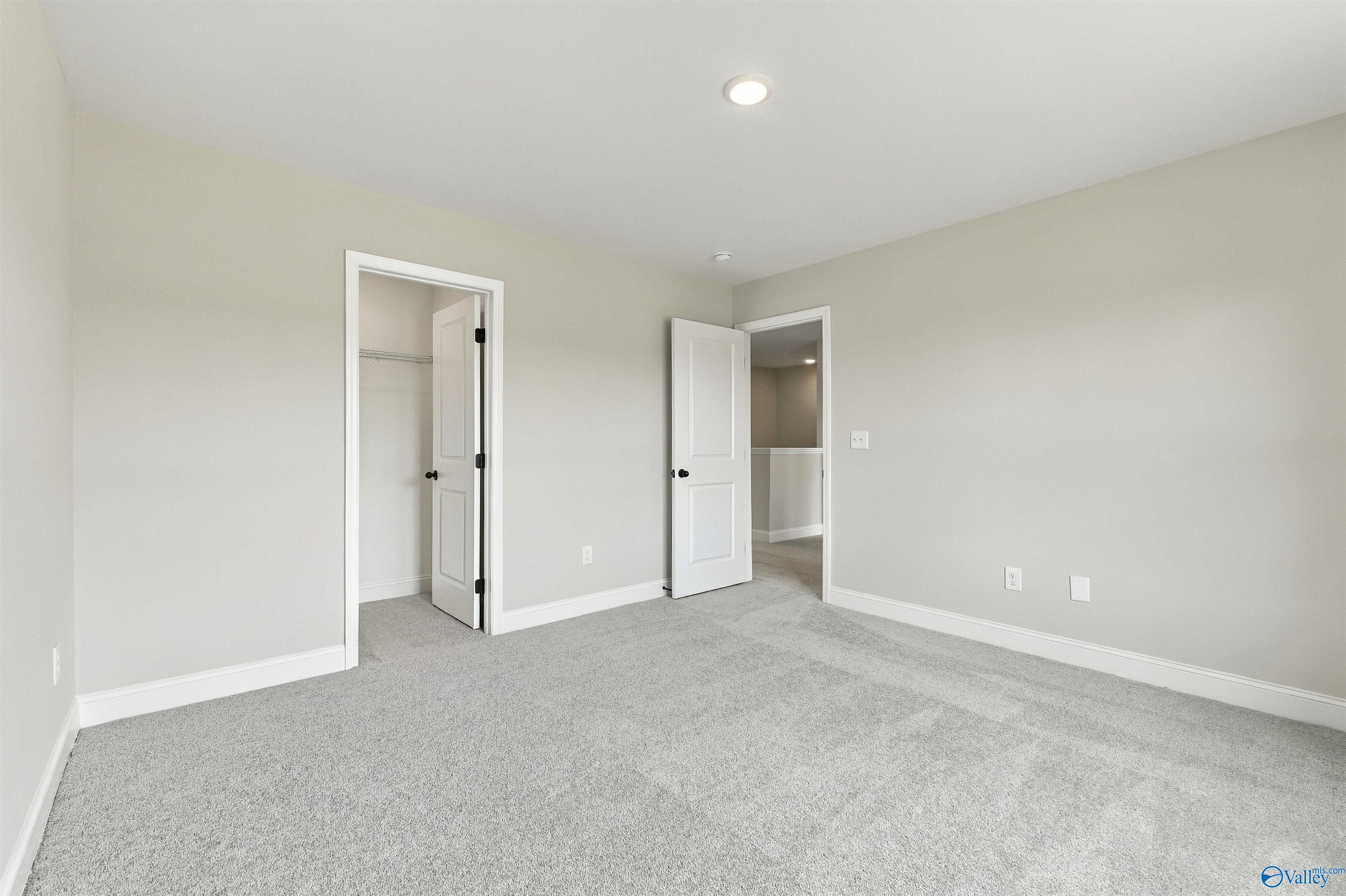 Spacious carpeted bedroom with walk-in closet in Davidson Homes The Shelby A, The Meadows, Athens, Alabama