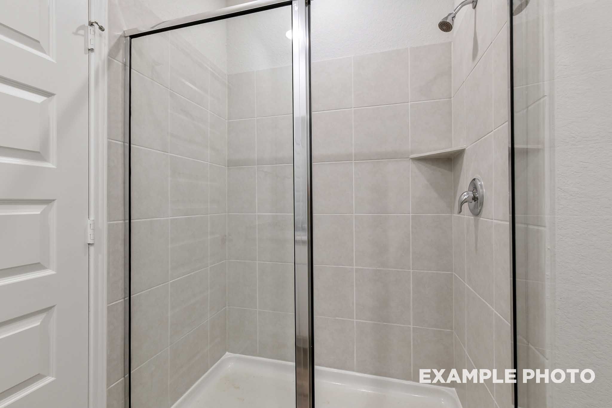 Tiled walk-in shower with glass enclosure in the master suite of The Frio home design by Davidson Homes.