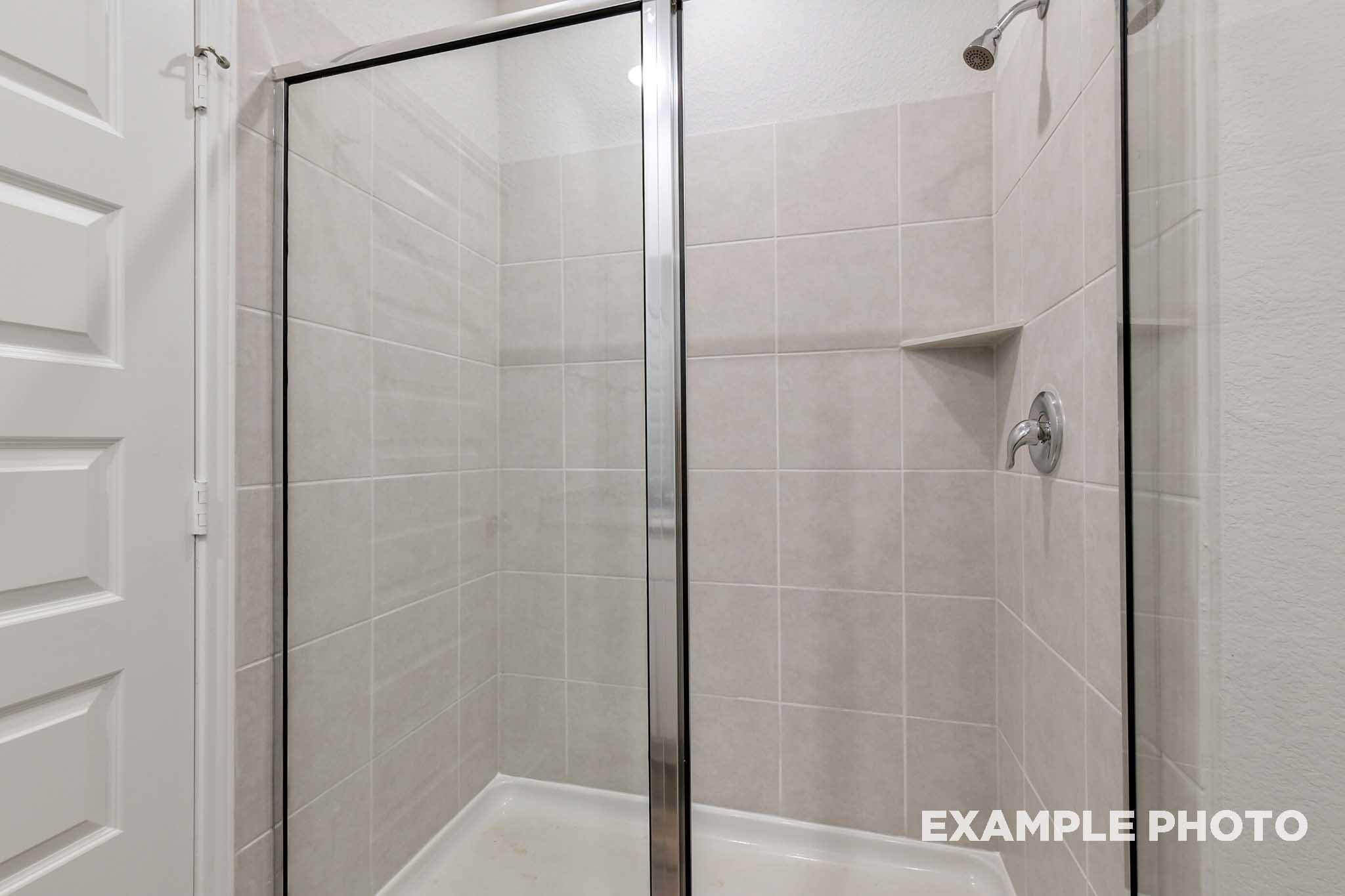 Tiled walk-in shower with glass enclosure in the master suite of The Frio home design by Davidson Homes.