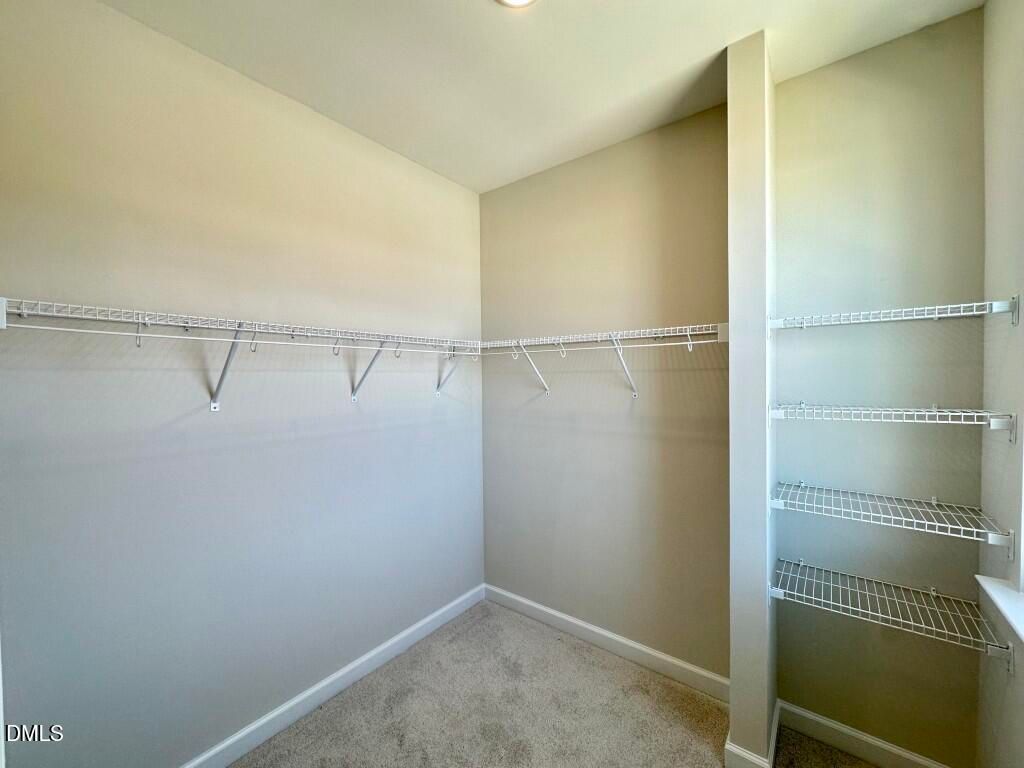 Spacious walk-in closet with white wire shelving and hanging rods in master suite, Davidson Homes The Burke, Knightdale NC