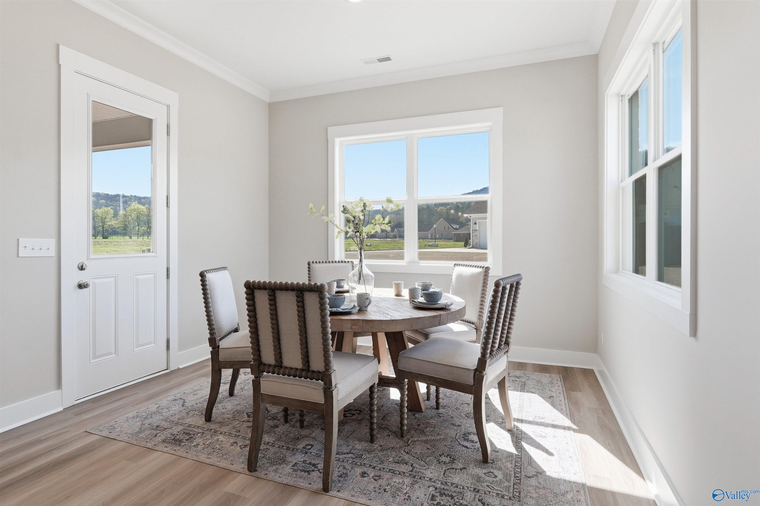 Elegant dining room featuring round wooden table, tufted chairs, and mountain views in Evermore Homes The Oxford B, Owens Cross Roads, AL