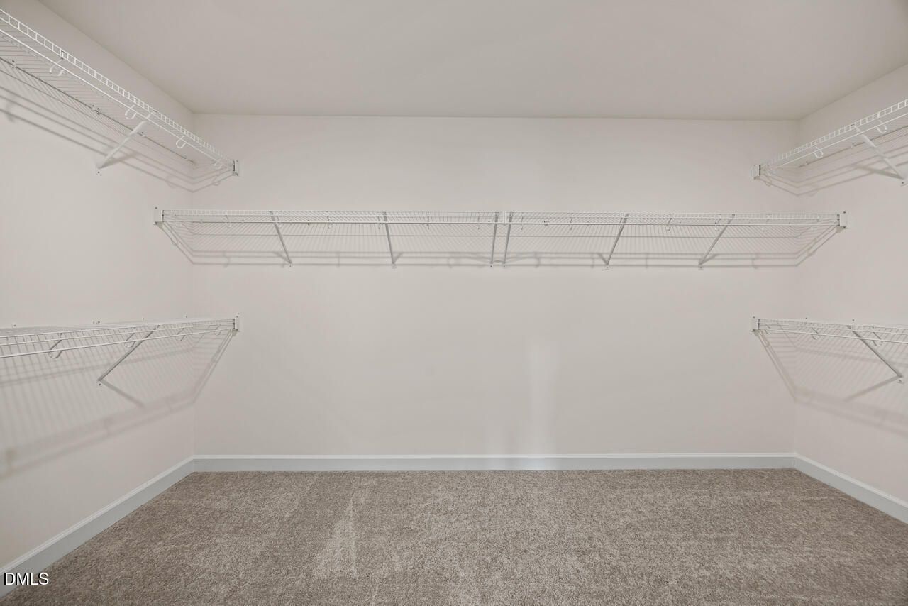Spacious walk-in closet with wire shelving and carpet flooring in Davidson Homes Hickory II B plan, Lillington, North Carolina