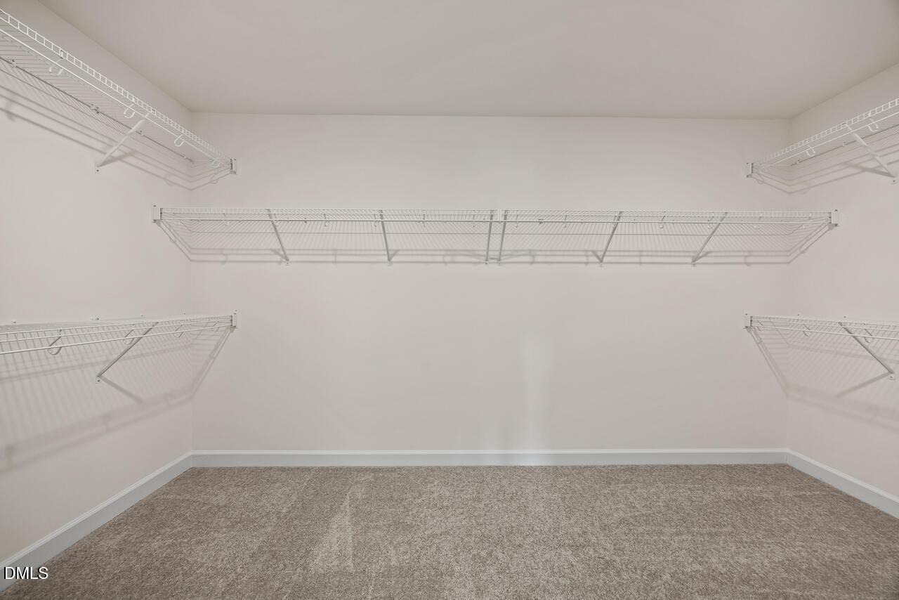Spacious walk-in closet with wire shelving and carpet flooring in Davidson Homes Hickory II B plan, Lillington, North Carolina