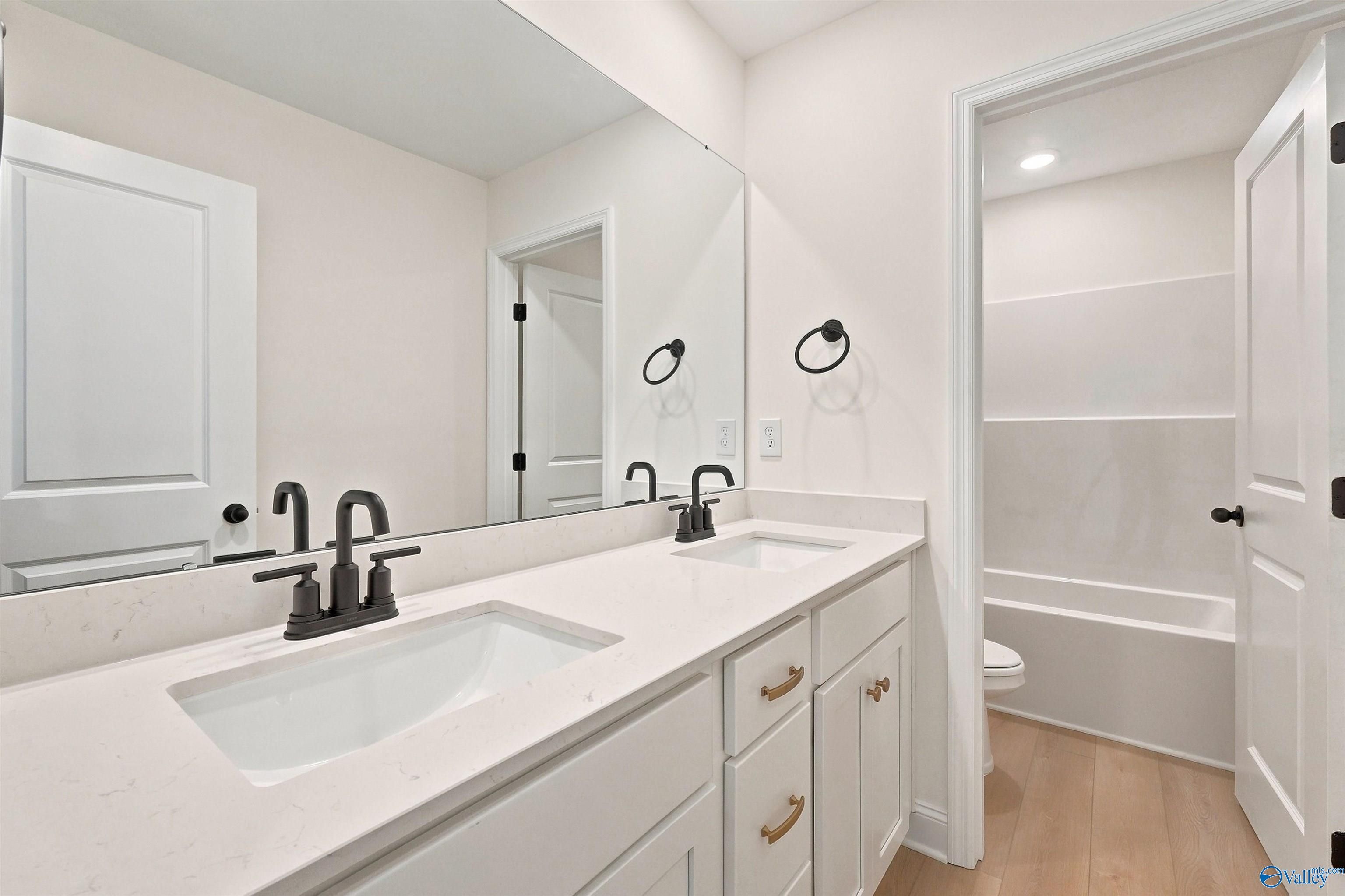 Double vanity bathroom with quartz countertops and black fixtures in The Chelsea C floor plan, Creek Grove, New Market, AL.