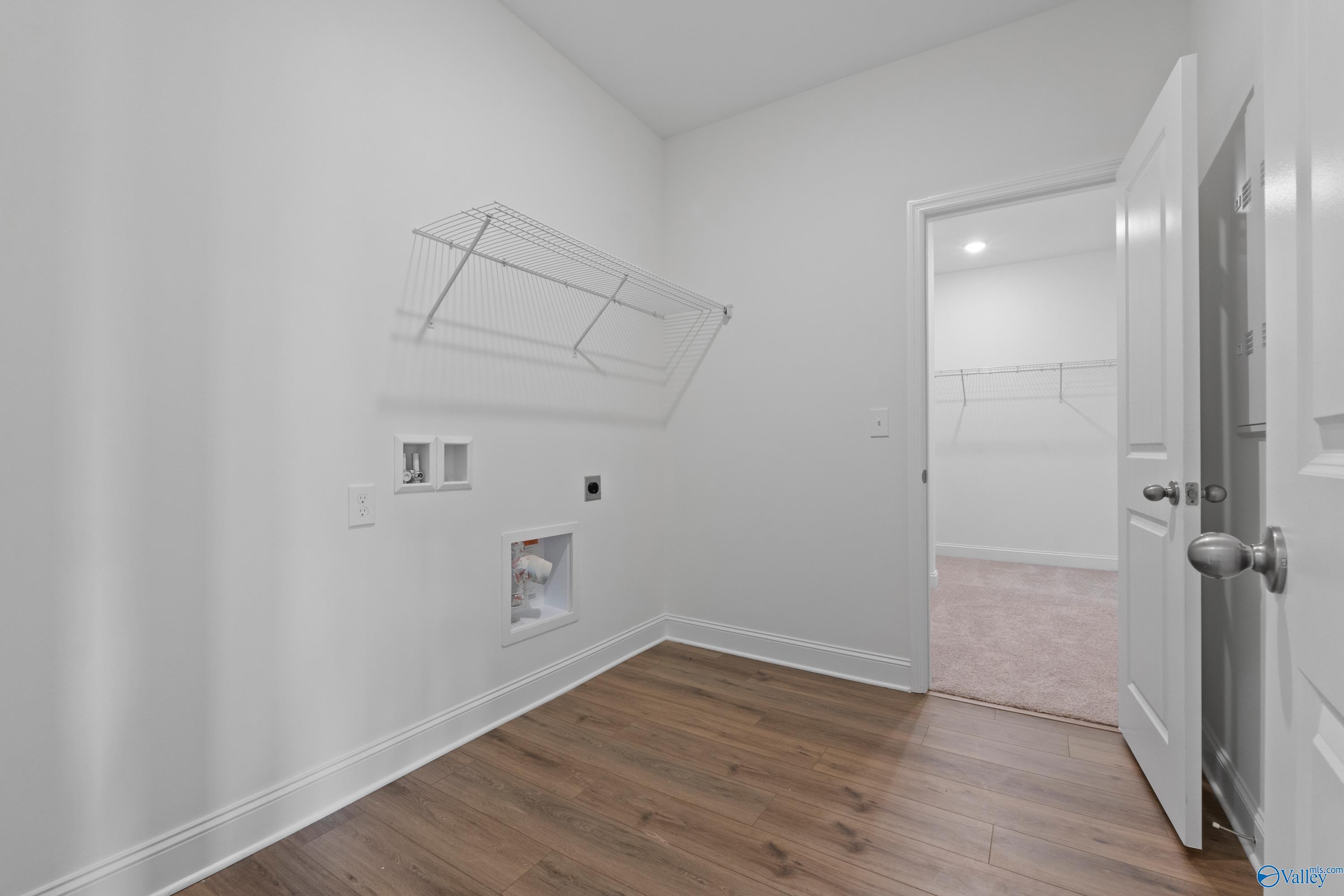 Laundry room with washer and dryer hookups and shelving in The Everett B floor plan, The Meadows, Athens, Alabama.