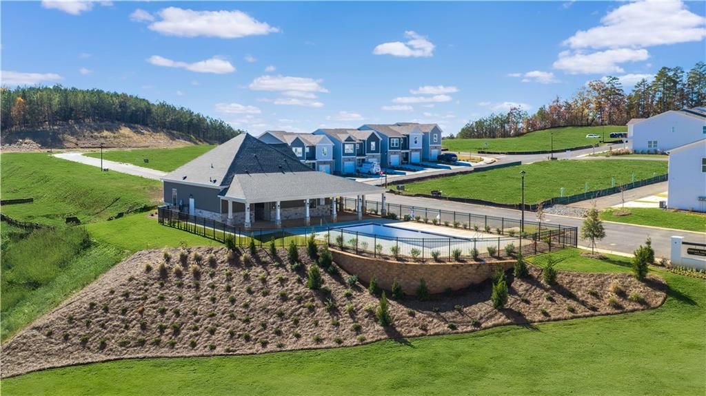 Aerial view of fenced community swimming pool and pavilion surrounded by modern homes and green hills in Stegall Village, Emerson, Georgia