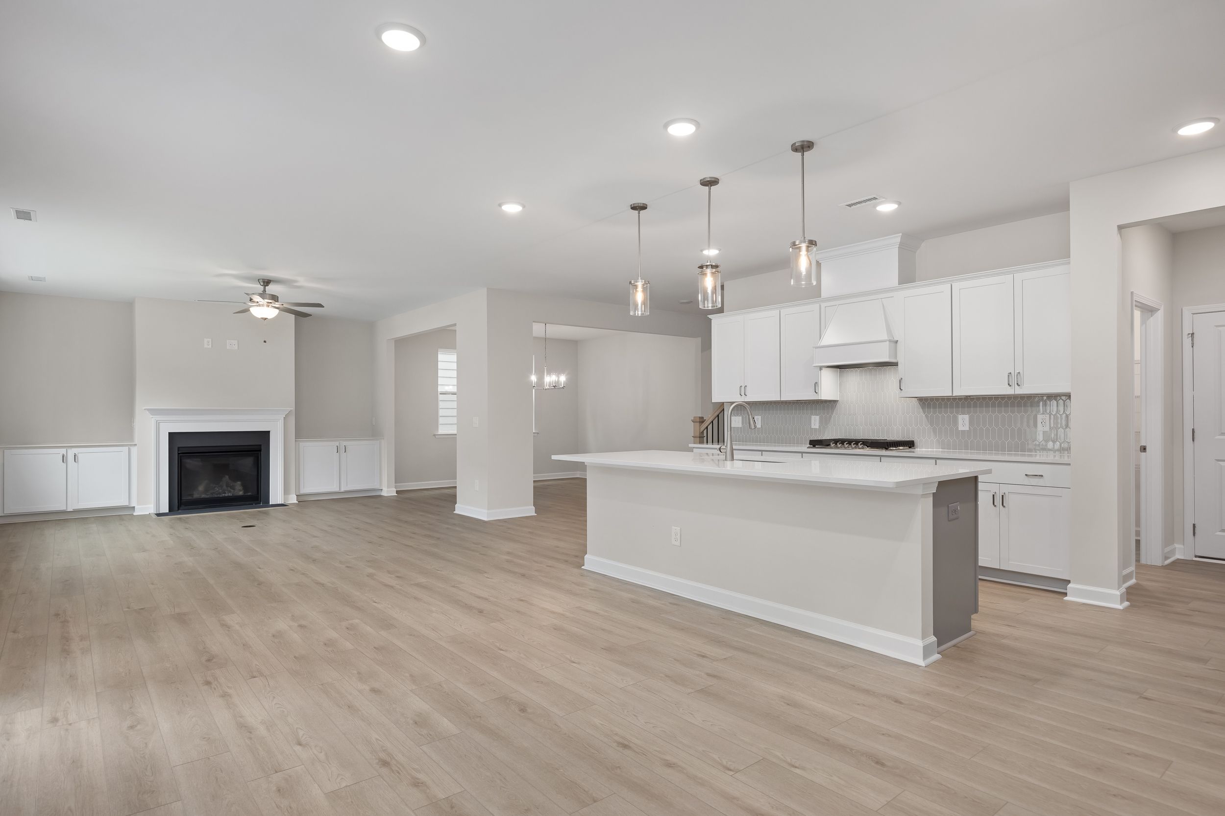 Open-concept kitchen and living space in The Beech Davidson Homes design with white cabinets, large island, gas range, and fireplace