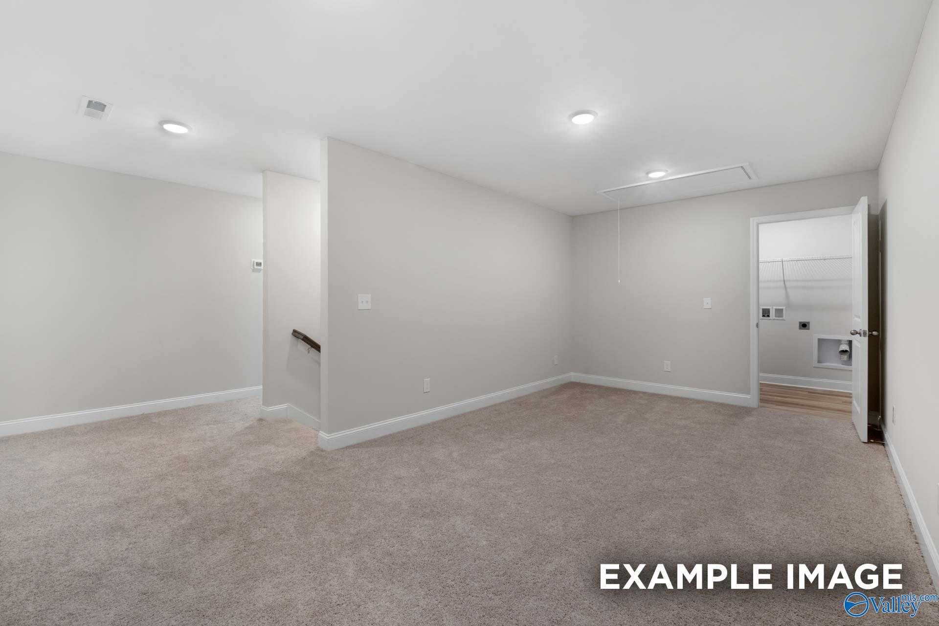 Spacious upstairs bonus room with beige carpet, staircase, and utility door in The Camden 3-bedroom home, Huntsville, Alabama