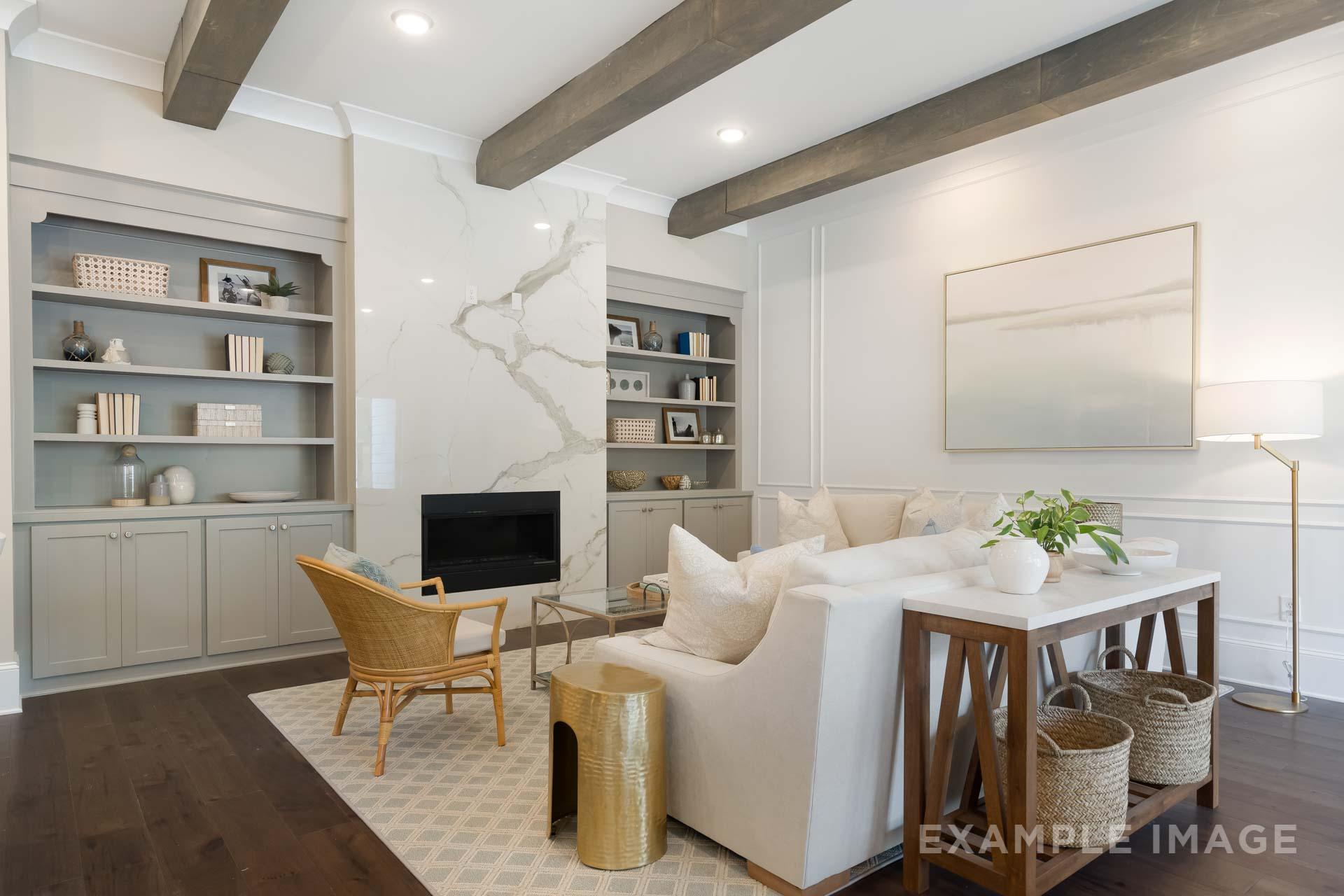 Cozy living room in The Seaside home by Davidson Homes, Woodstock GA: beamed ceiling, white quartz fireplace, built-in shelves, plush sofa