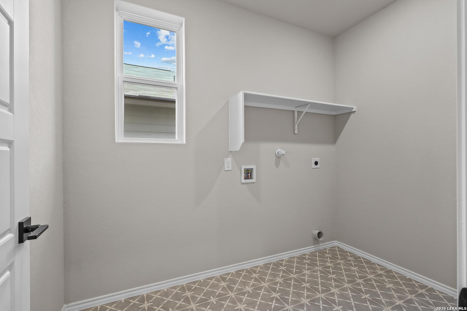 Laundry room with white shelf, window, and patterned tile floor in Davidson Homes Sequoia C plan, Royal Crest, San Antonio