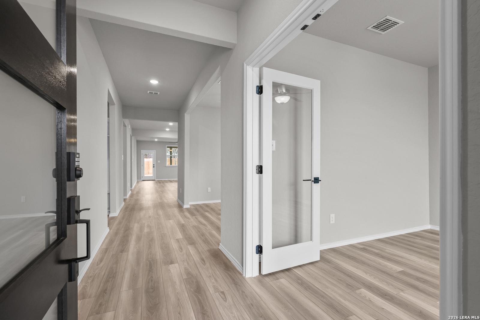 Spacious entry hallway with light wood floors, gray walls, and glass French doors in The Glenwood F, Davidson Homes, San Antonio
