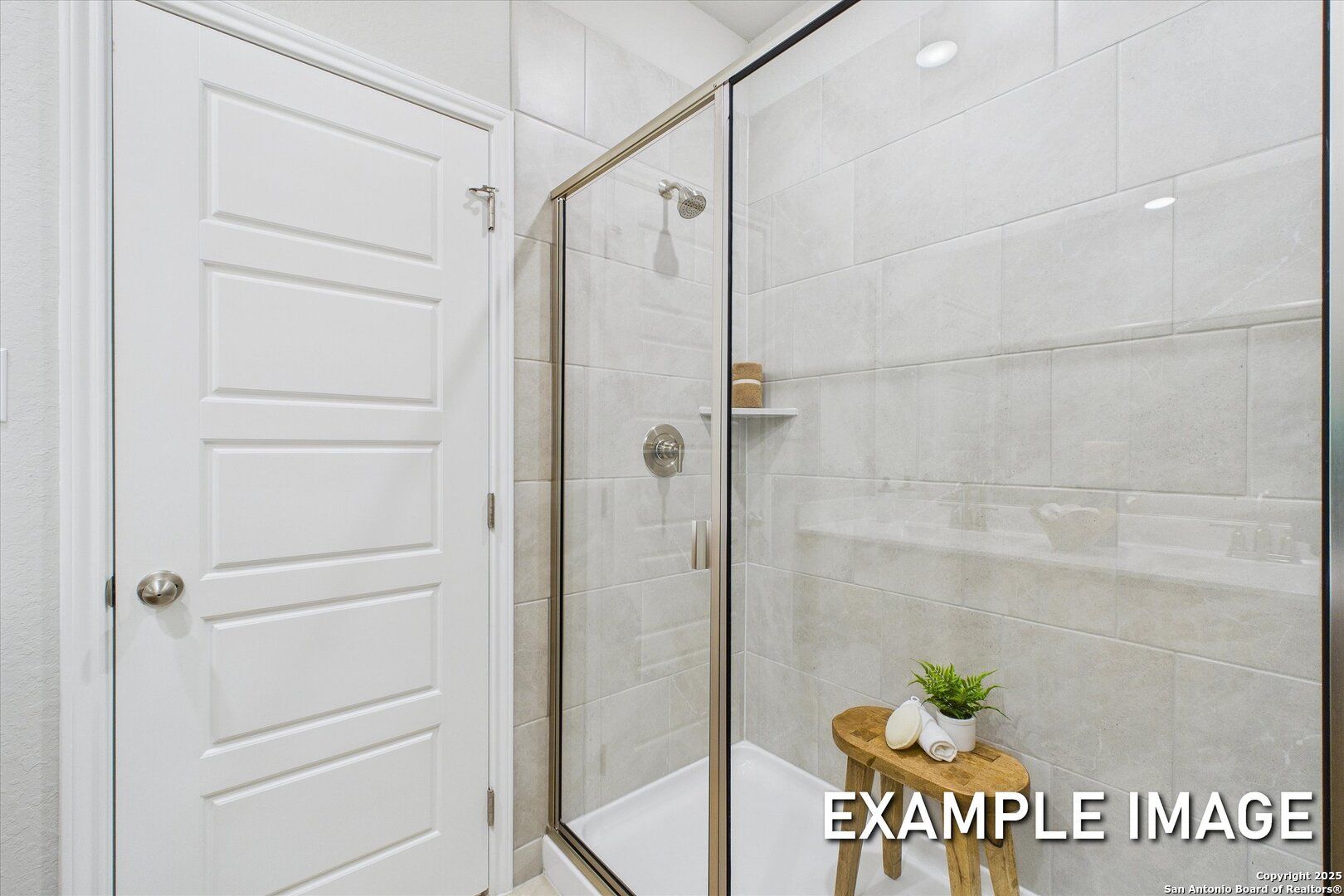 Modern master bathroom with frameless glass shower, white subway tiles, and teak stool in Davidson Homes The Sabine C, Agave TX