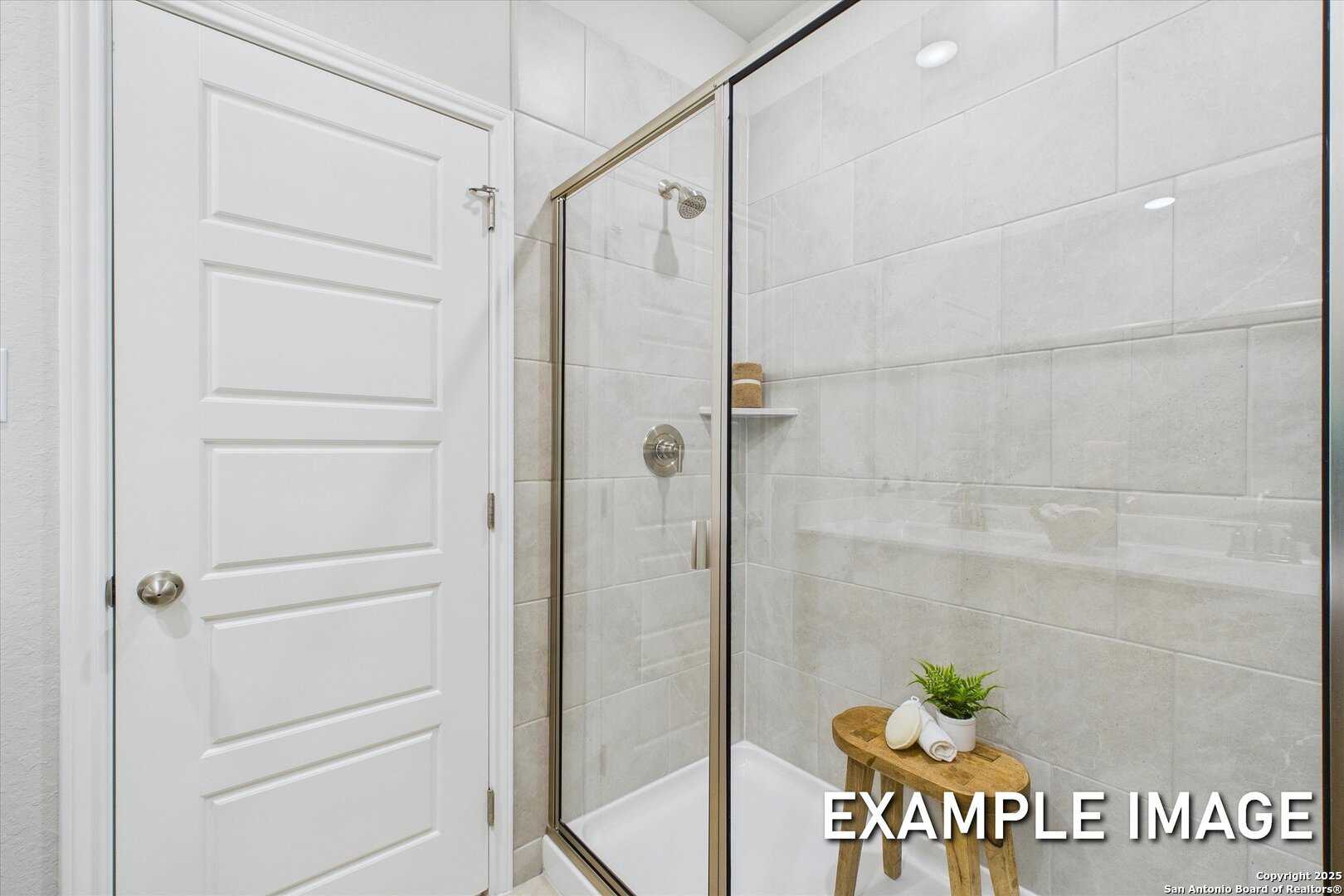 Modern walk-in shower with frameless glass enclosure, white subway tiles, and teak stool in Davidson Homes The Sabine C, San Antonio