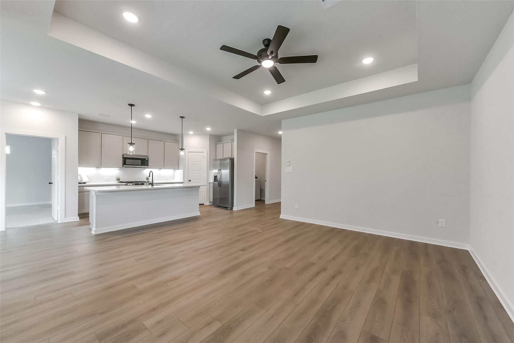 Open-concept kitchen with white island, stainless appliances, pendant lights, and hardwood floors in The Everett C, Crosby, Texas