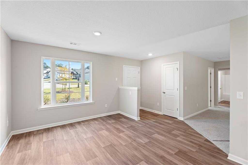 Bright bedroom with large window view of yard, hardwood floors, and walk-in closet doors in Davidson Homes The Washington, Phenix City