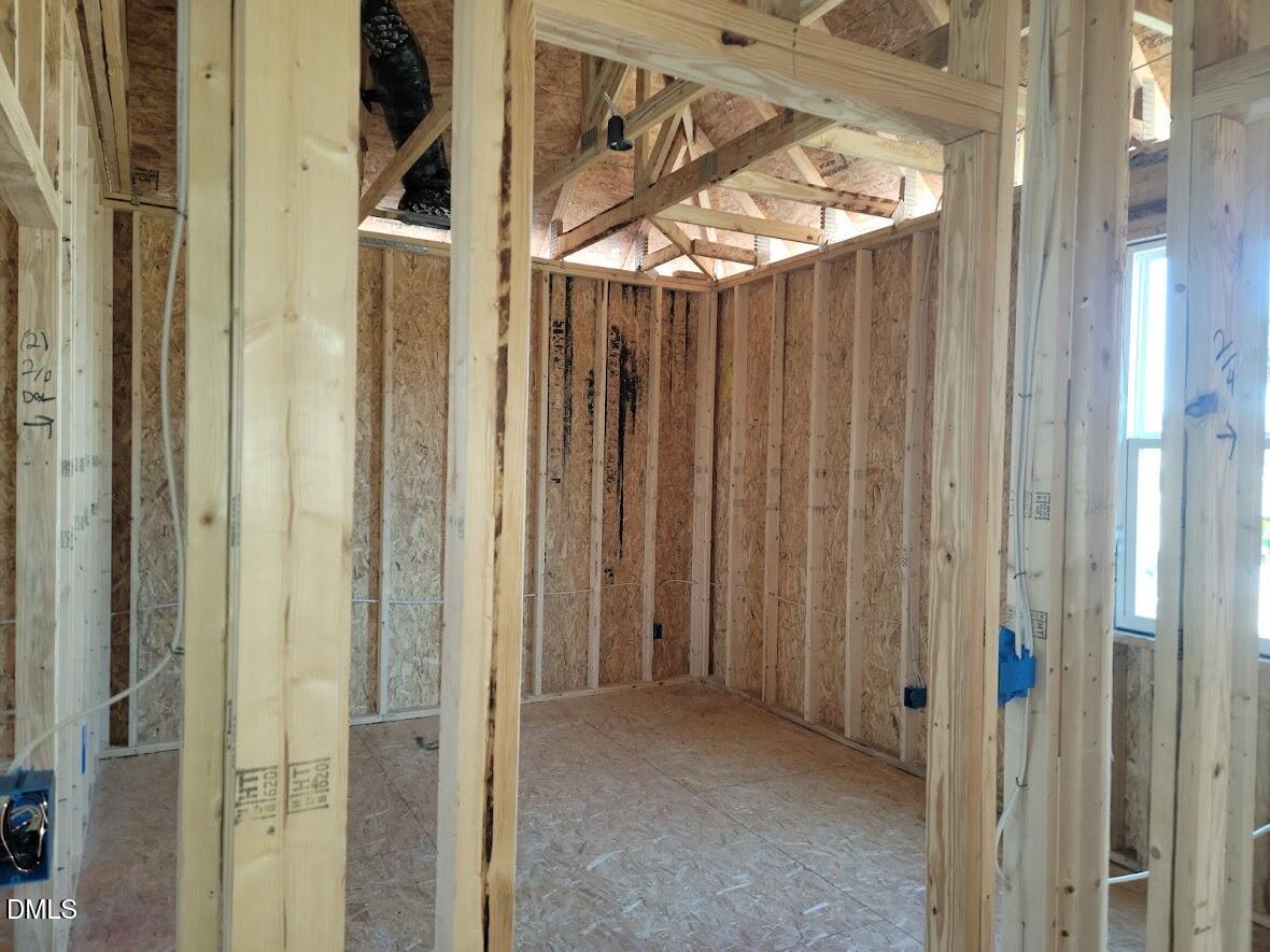 Exposed wooden framing with plywood sheathing and electrical wiring in unfinished room of The Ashport G 5-bedroom home in Angier, North Carolina
