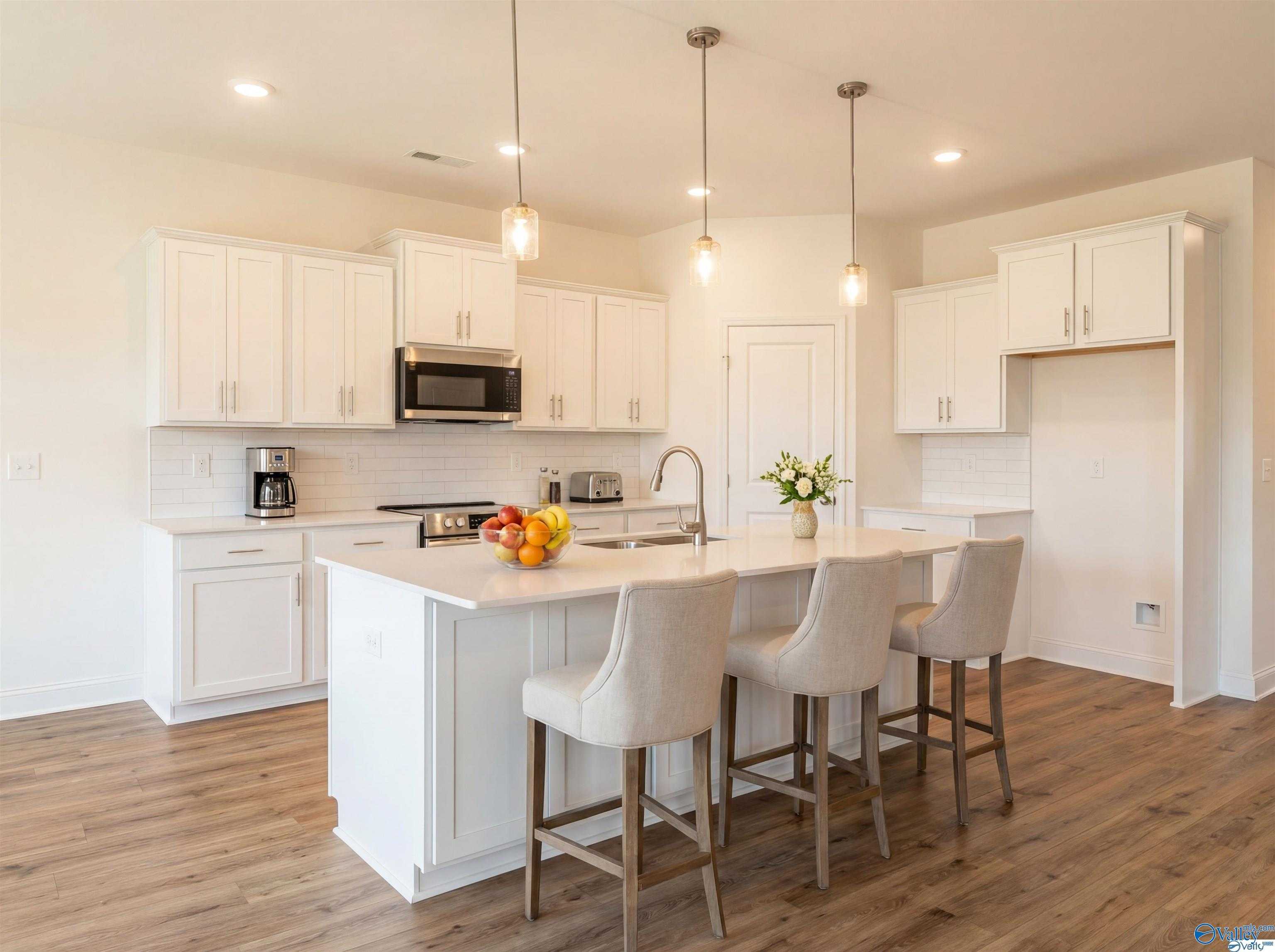 Bright white kitchen with large island, stainless appliances, pendant lights in Davidson Homes The Rockford B, Toney, Alabama