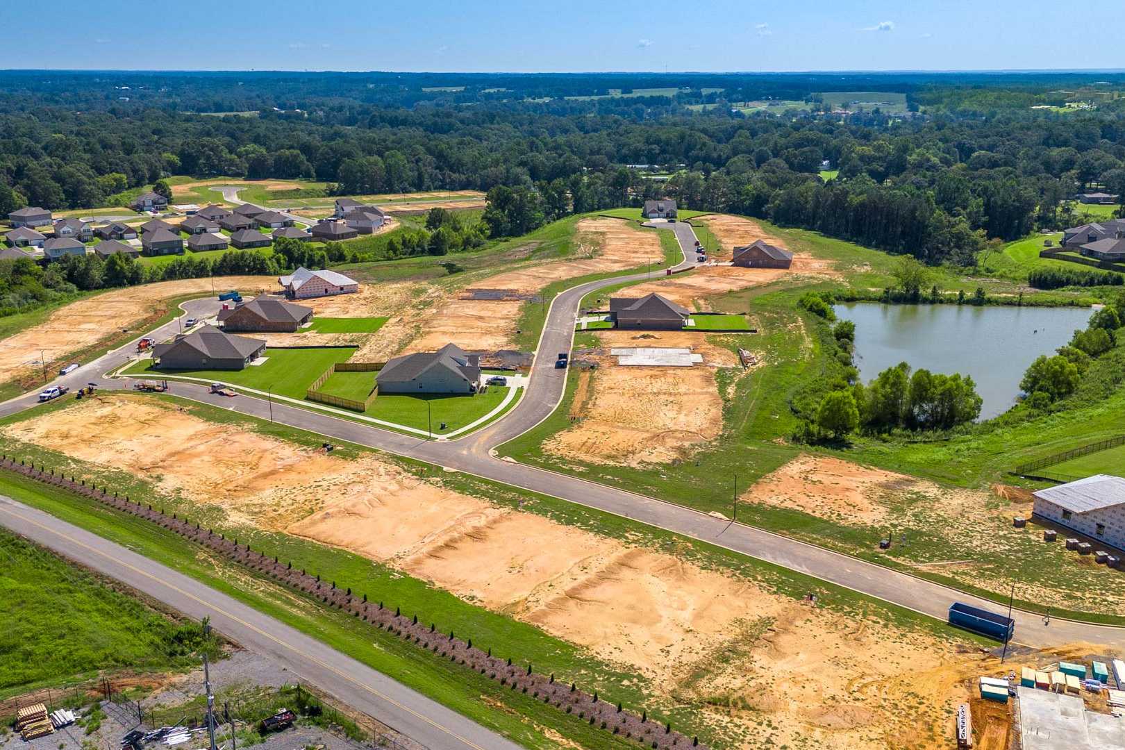 Aerial view of North Ridge neighborhood in Cullman Alabama featuring new homes under construction, pond, wooded lots, and developing streets by Davidson Homes