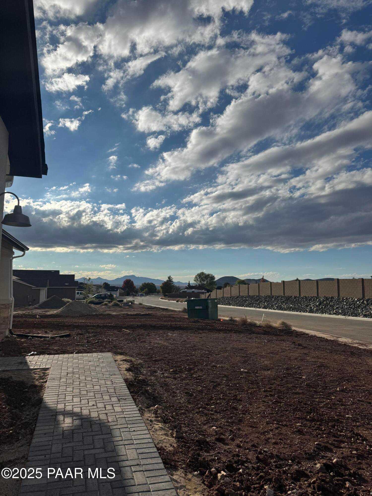Modern 1-story home exterior with brick walkway, mountain backdrop, and partly cloudy skies in Morningstar, Prescott Valley, Arizona