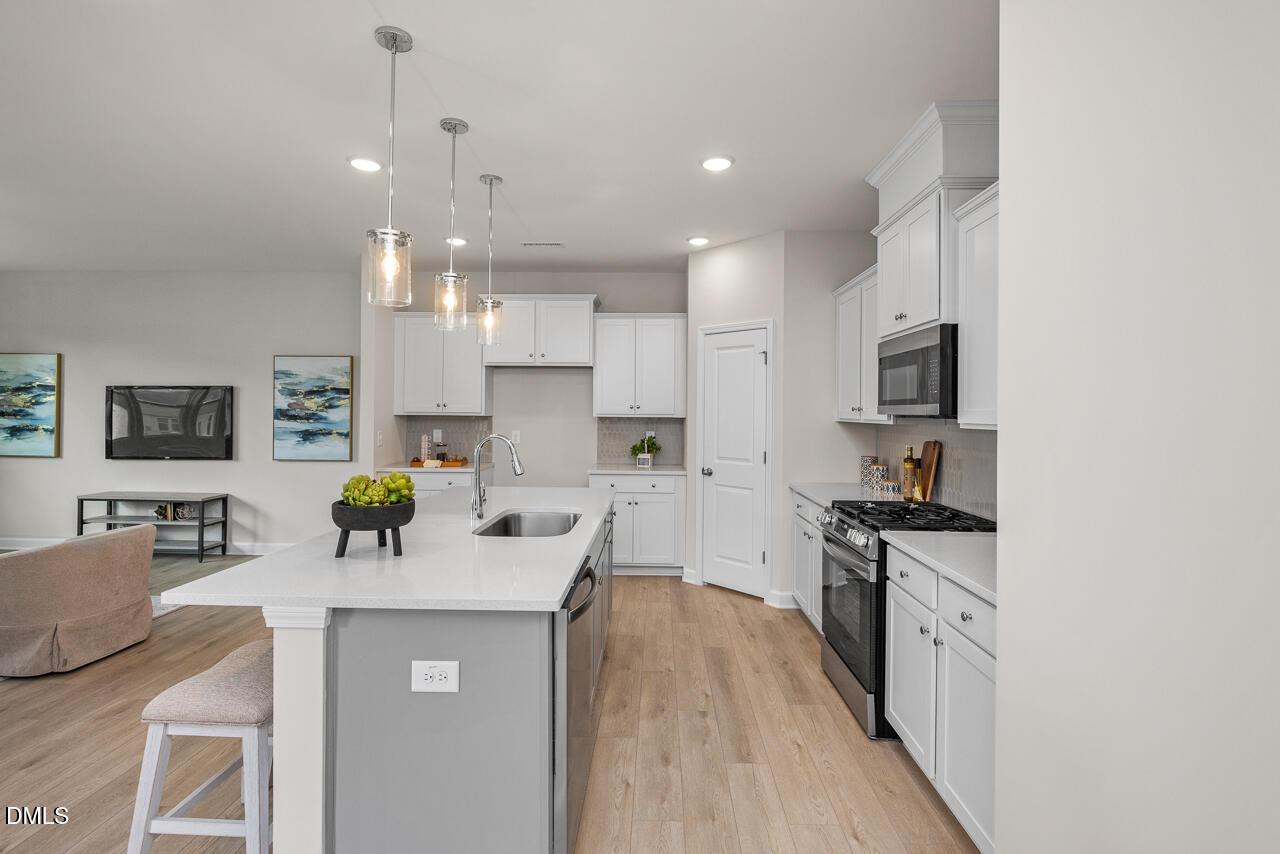 Modern open-concept kitchen with white shaker cabinets, quartz island sink, stainless appliances in 4-bed Preston A home, Lillington NC
