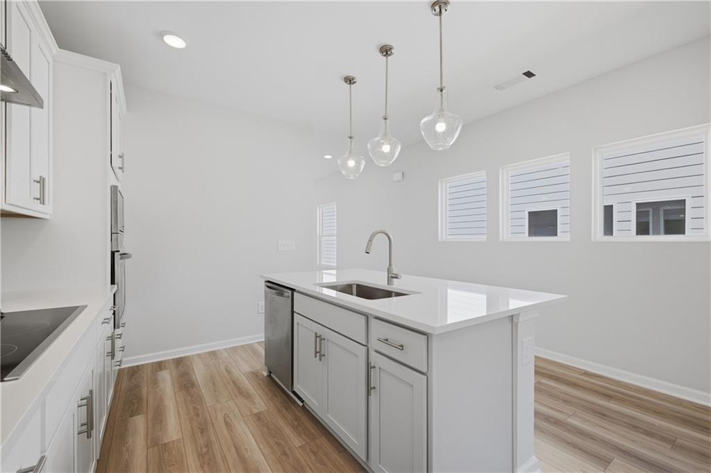 Bright white kitchen with center island, pendant lights, and hardwood floors in Davidson Homes The Oconee B, Canton, Georgia