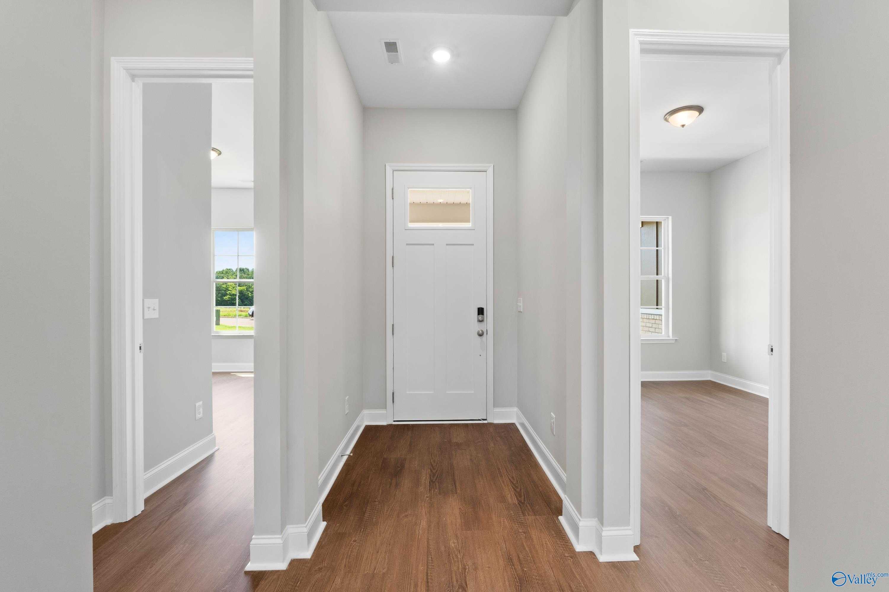 Bright entry hallway with hardwood floors, white doors, and window views in The Arcadia 4-bedroom home, Riverton Preserve, Huntsville