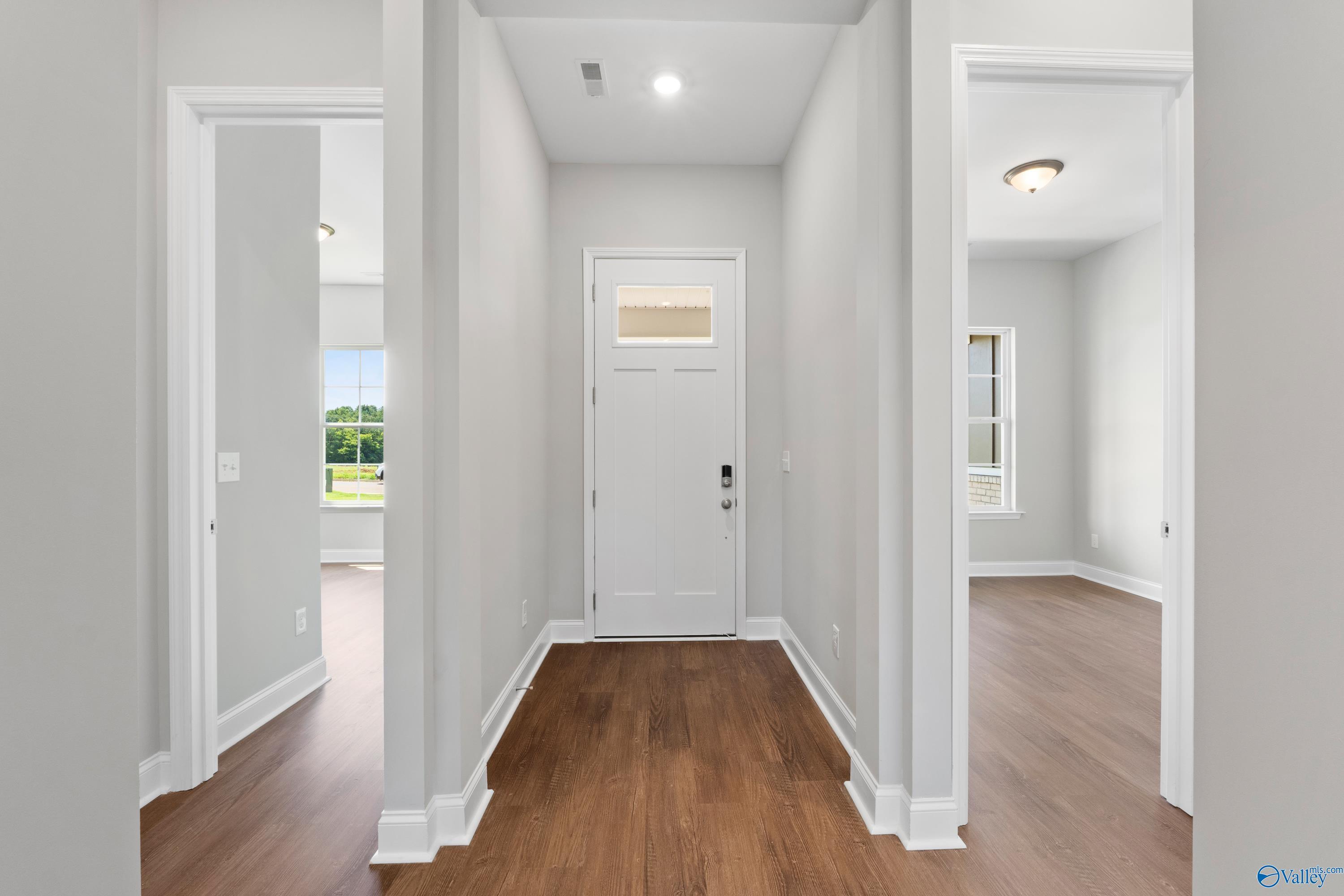 Elegant hallway with hardwood floors, white doors, and natural light views in Davidson Homes The Arcadia B, Huntsville