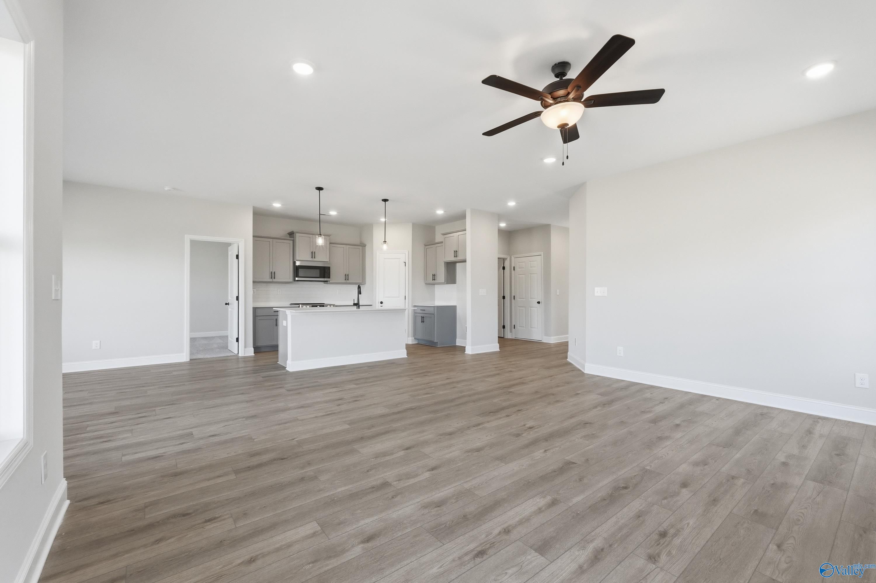 Open-concept kitchen with white cabinets, island, and stainless appliances in 3-bedroom Davidson Homes Franklin C, New Market, AL