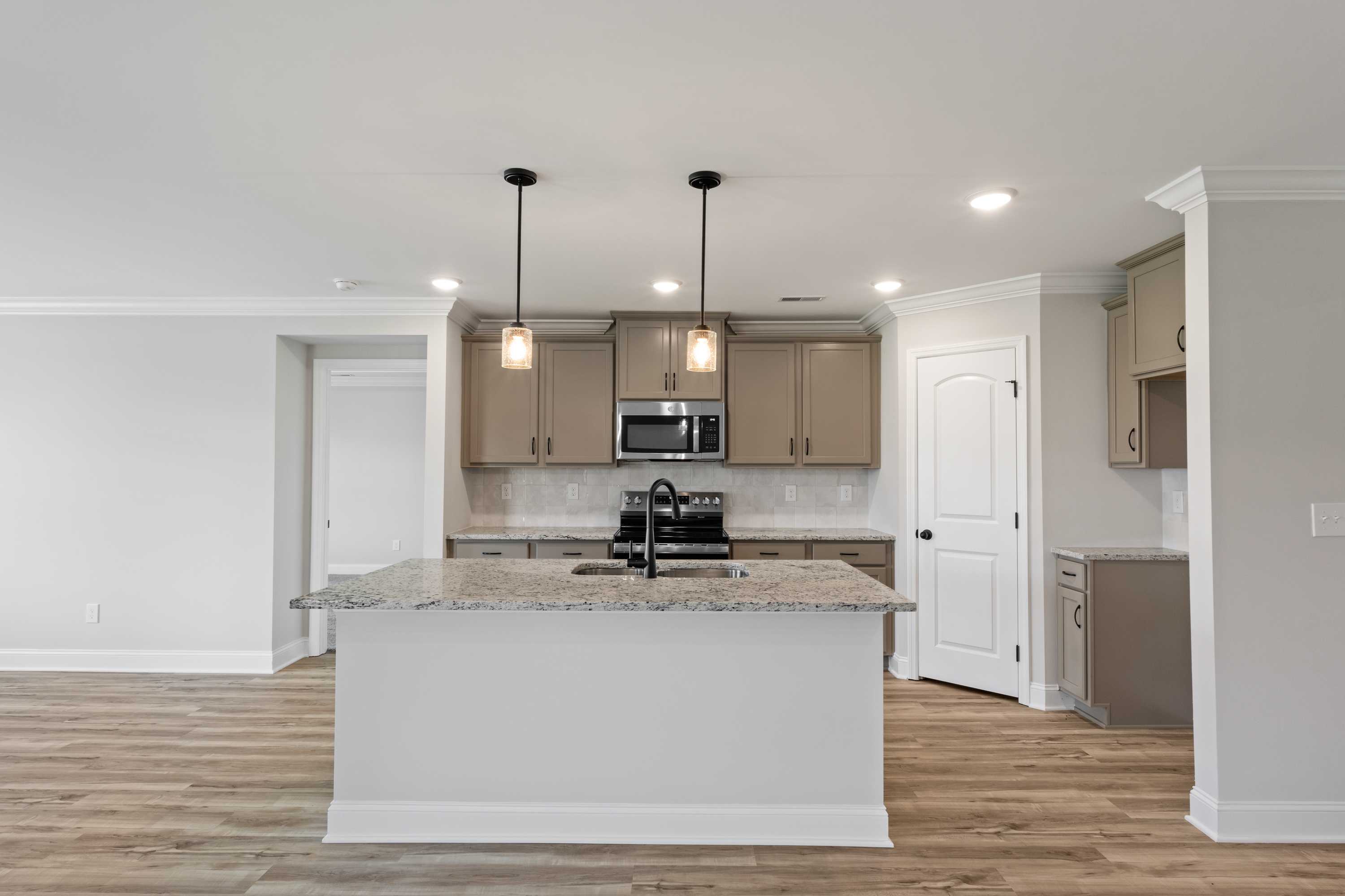 Gourmet kitchen in The Everett C with large white island, granite counters, stainless appliances, and wood floors