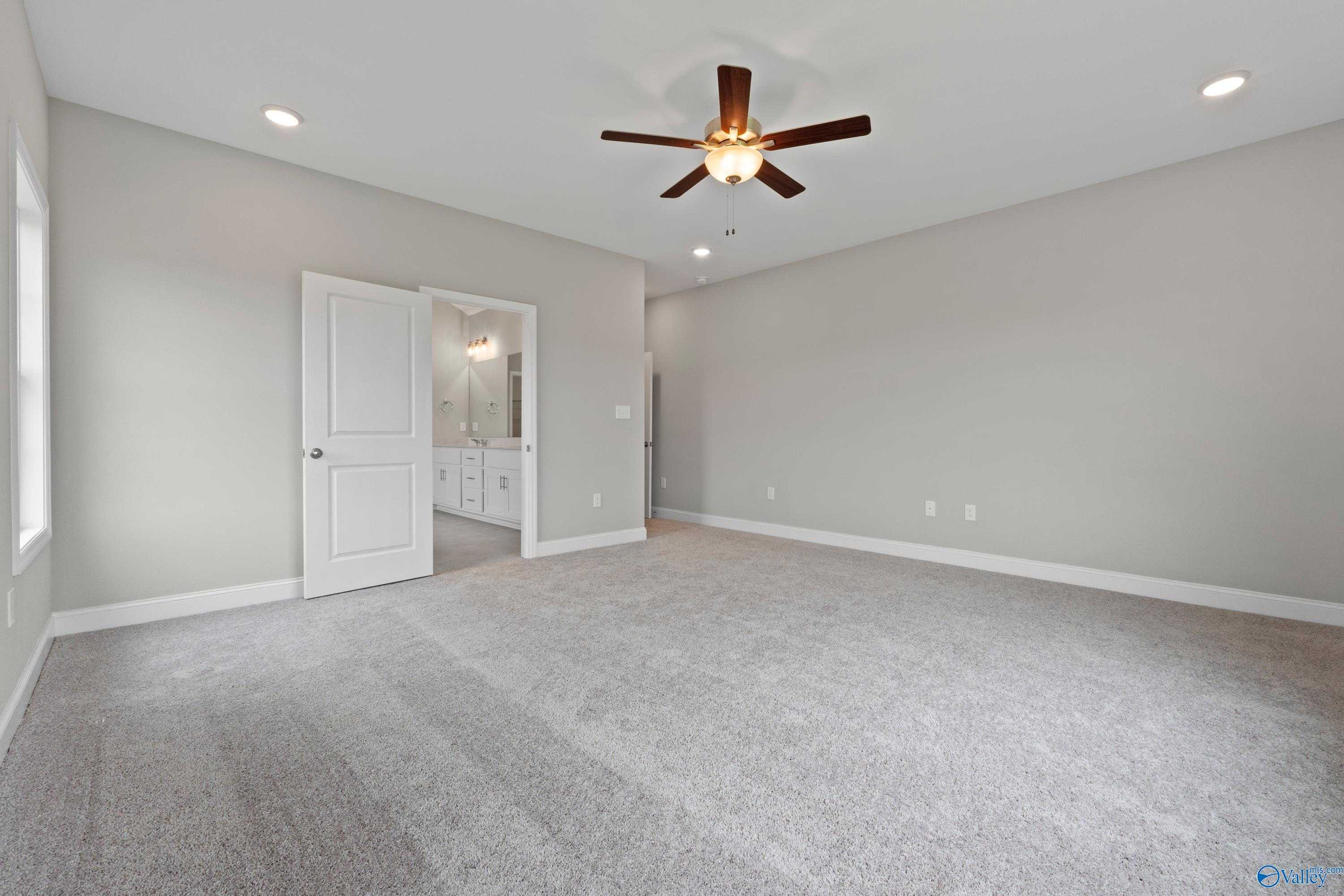 Spacious master bedroom with en-suite bath, ceiling fan, and plush carpet in Davidson Homes The Finleigh, Meridianville, Alabama