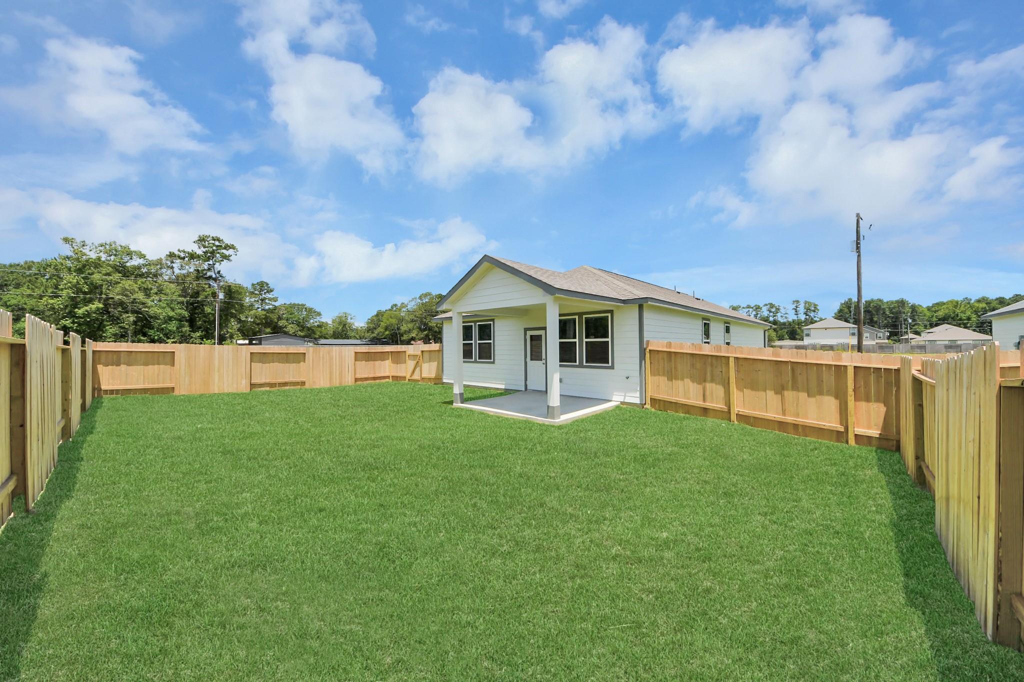 Covered back patio and fenced backyard of The Frio F floor plan home in Liberty Estates, Cleveland, Texas.