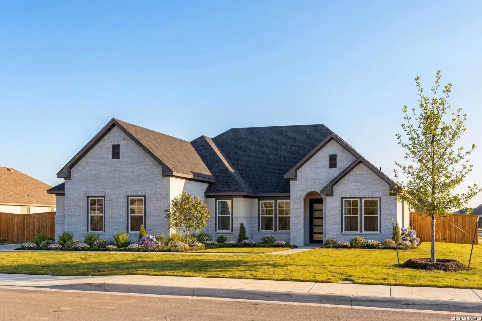 Two-story Davidson Homes Foster F plan with stone exterior and landscaped yard in Potranco Oaks, Castroville, Texas.
