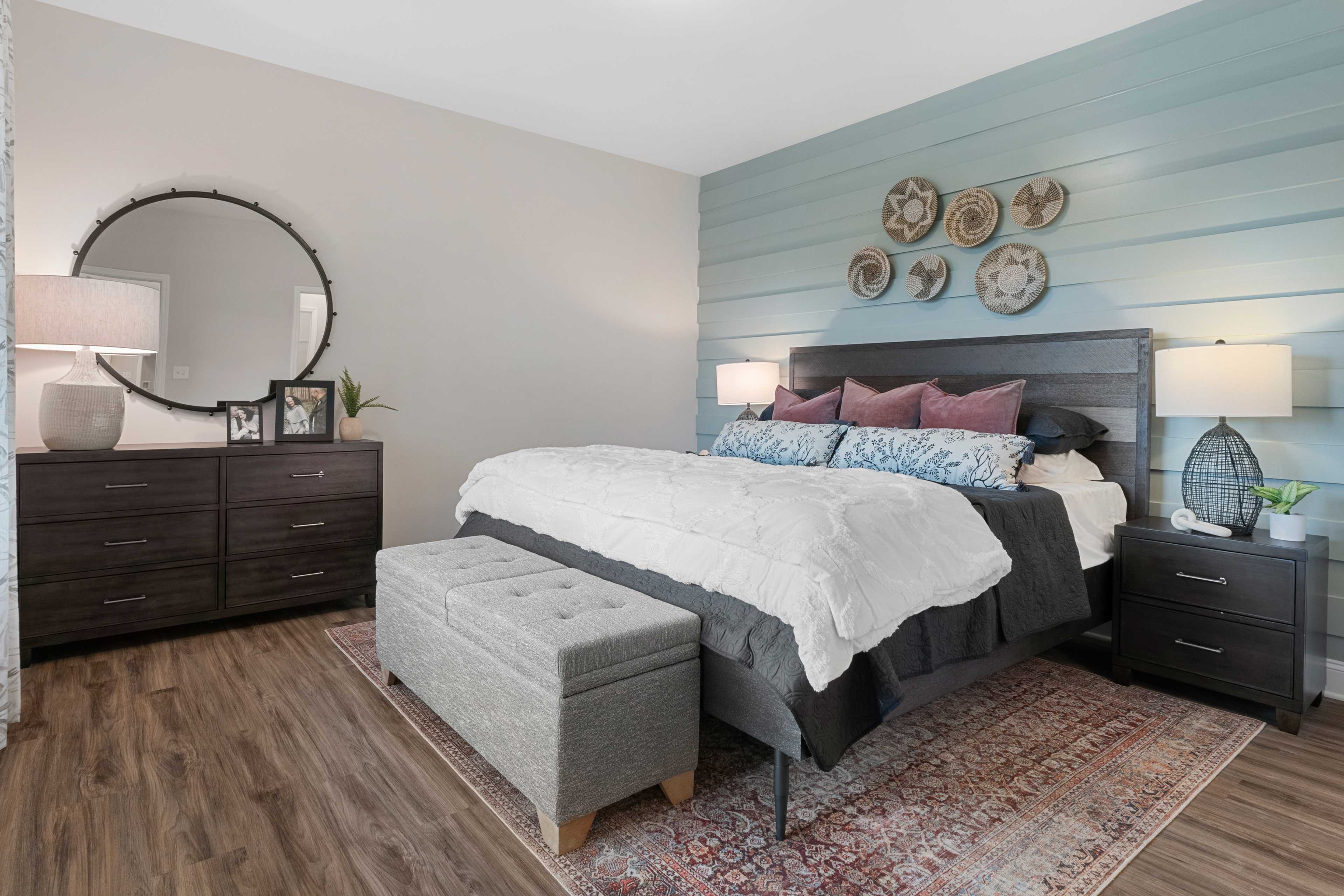 Cozy master bedroom at The Retreat at Cain Park in Hartselle AL with wooden headboard, woven baskets, and hardwood floors