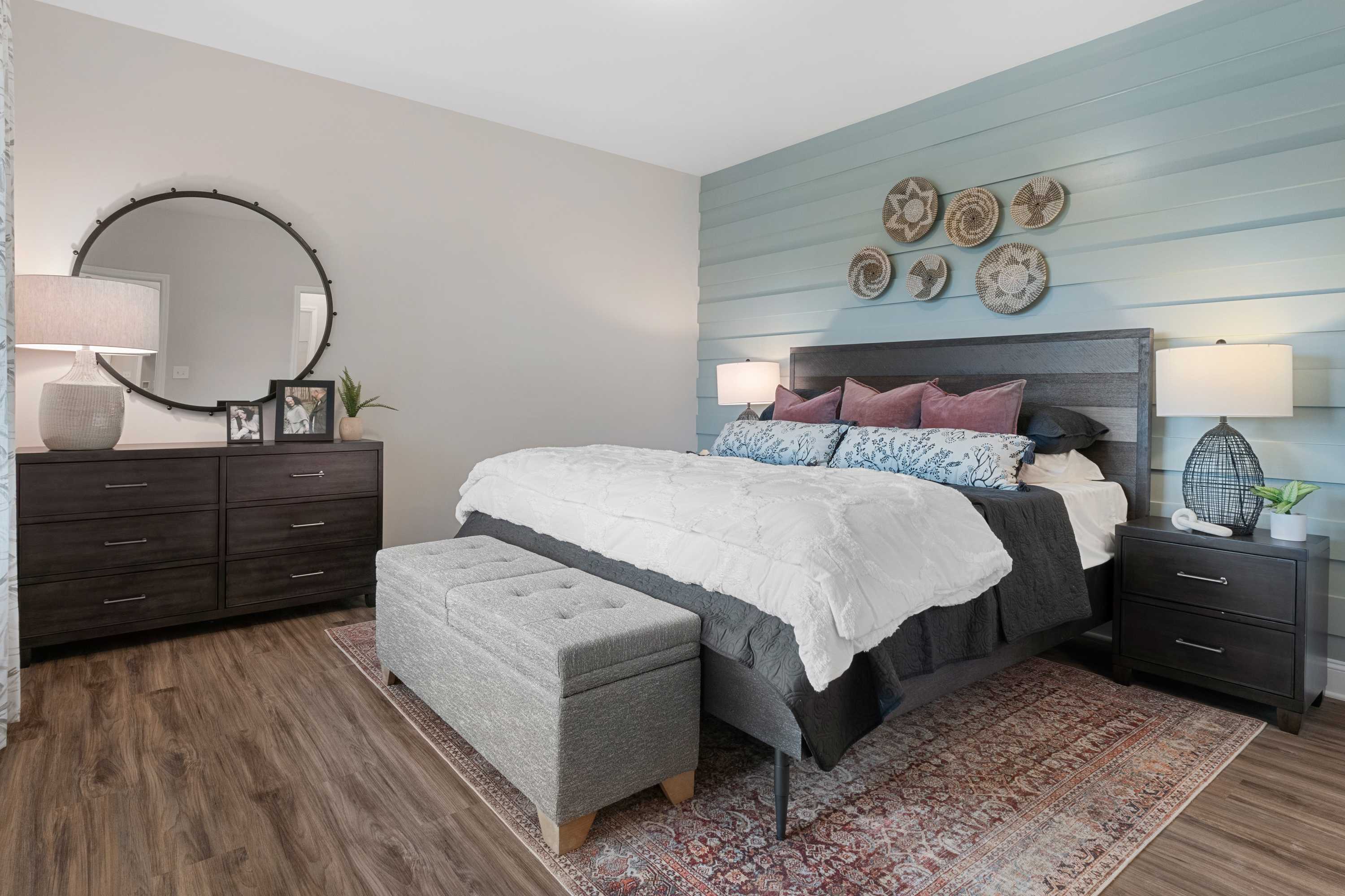 Cozy master bedroom at The Retreat at Cain Park in Hartselle AL with wooden headboard, woven baskets, and hardwood floors