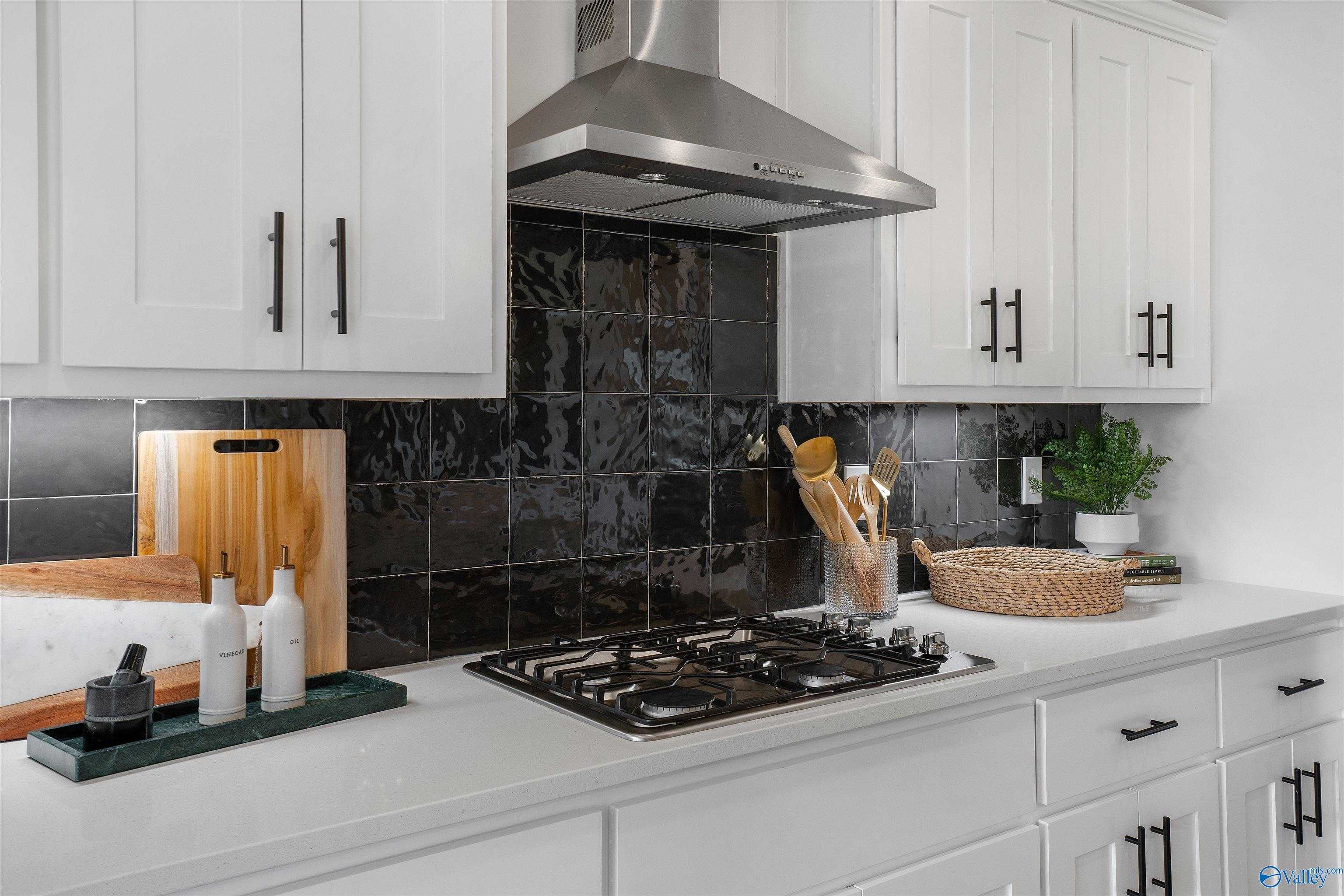 Modern kitchen featuring white shaker cabinets, black subway tile backsplash, stainless steel gas range in Davidson Homes The Rockford B, Madison AL