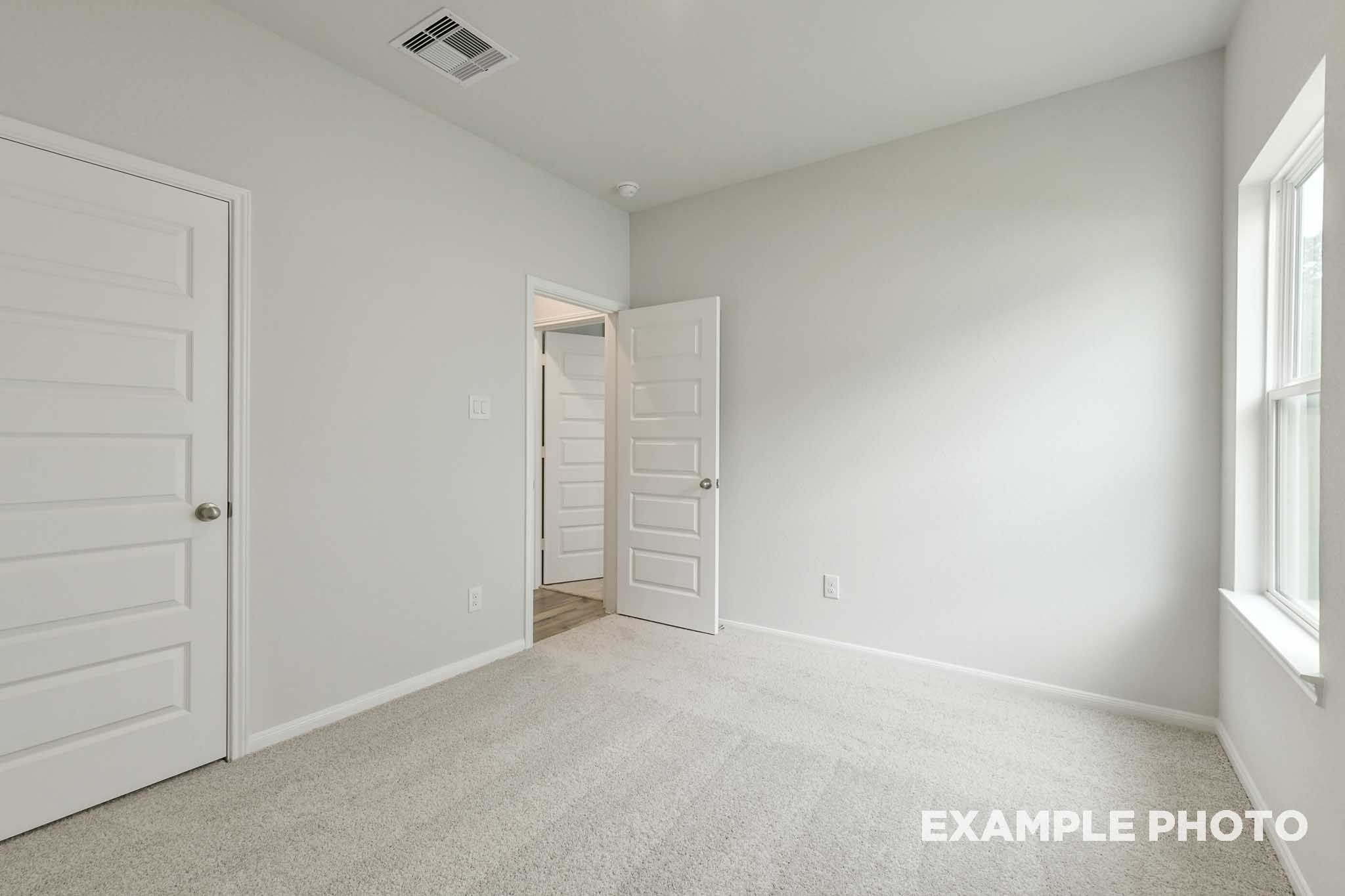 Bright, carpeted secondary bedroom in The Frio floor plan by Davidson Homes featuring neutral walls and natural light.