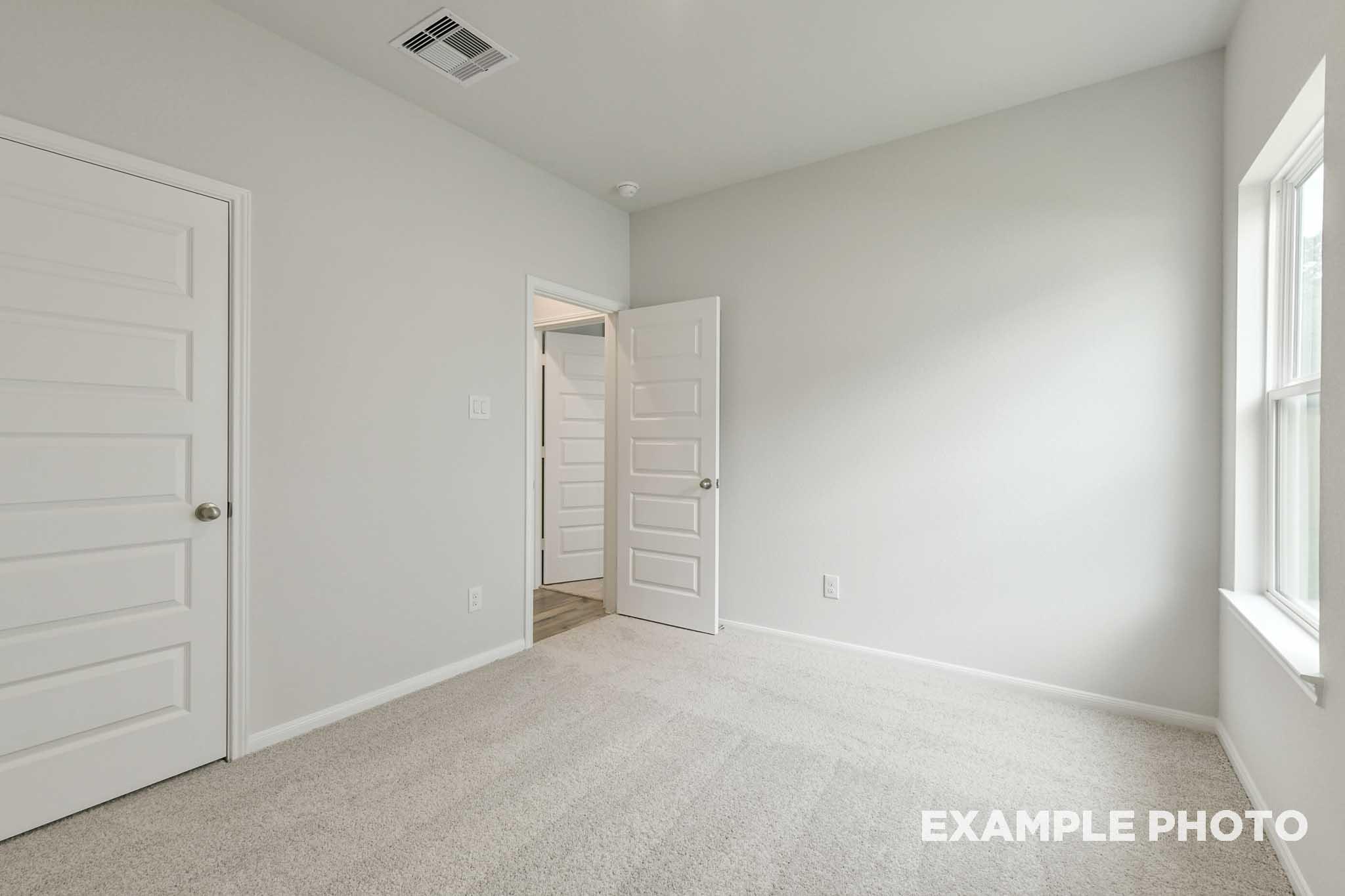 Bright, carpeted secondary bedroom in The Frio floor plan by Davidson Homes featuring neutral walls and natural light.