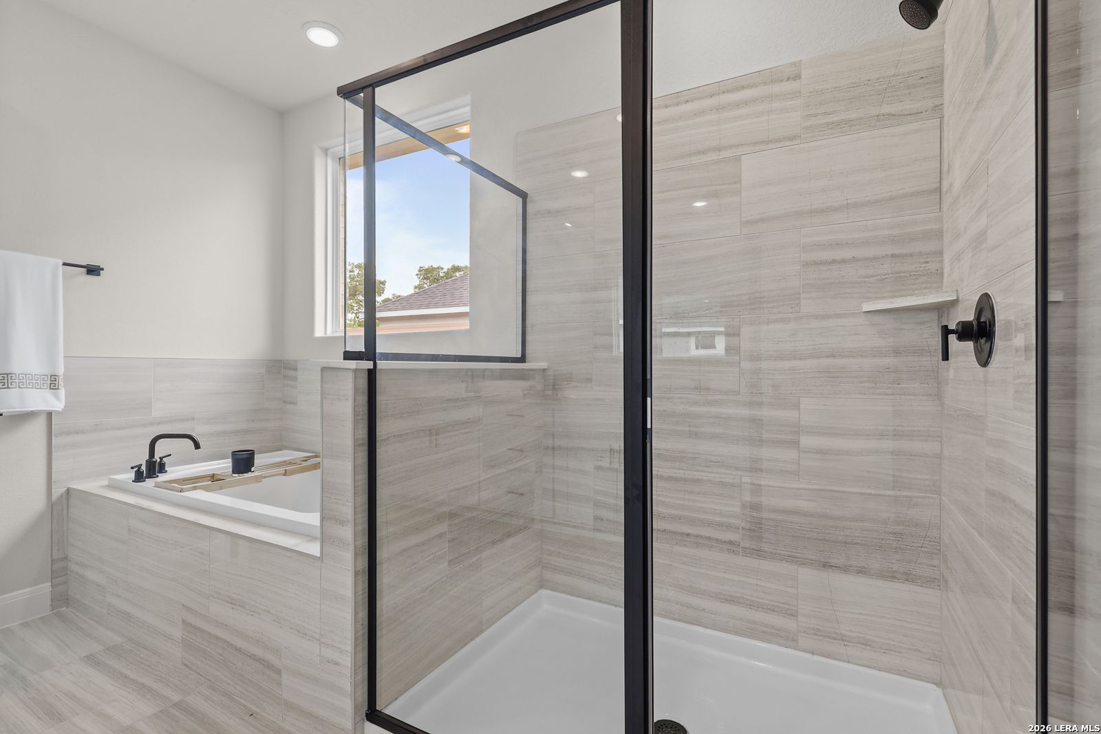 Modern master bathroom with frameless glass shower, freestanding soaking tub, and slate tile in The Lanier G, Castroville, Texas