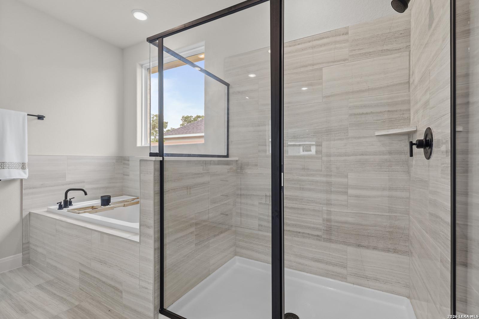 Modern master bathroom with frameless glass shower, freestanding soaking tub, and slate tile in The Lanier G, Castroville, Texas
