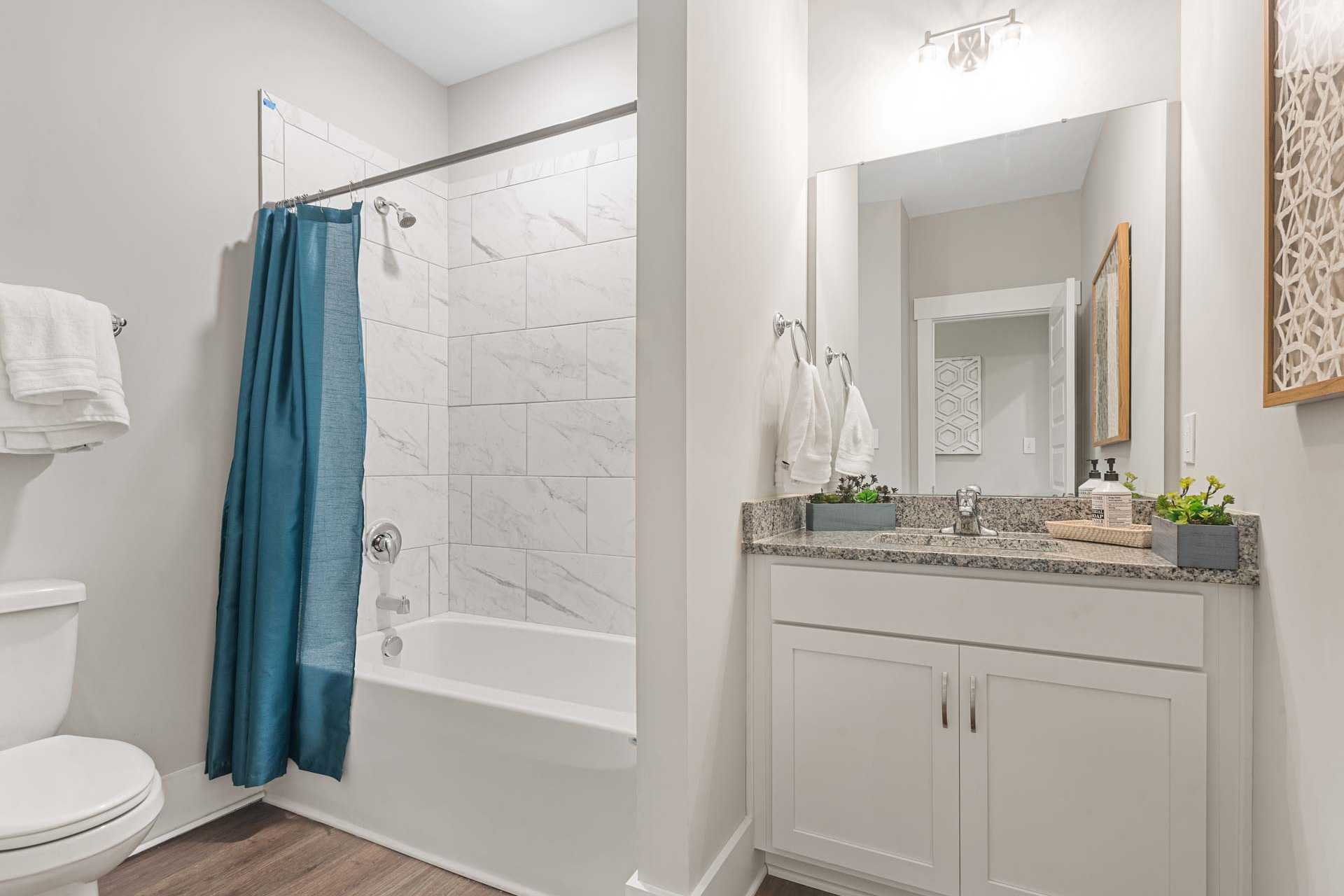 Spacious bathroom with teal shower curtain and bathtub at Monteagle Cove in Owens Cross Roads Alabama featuring white subway tile and double vanity