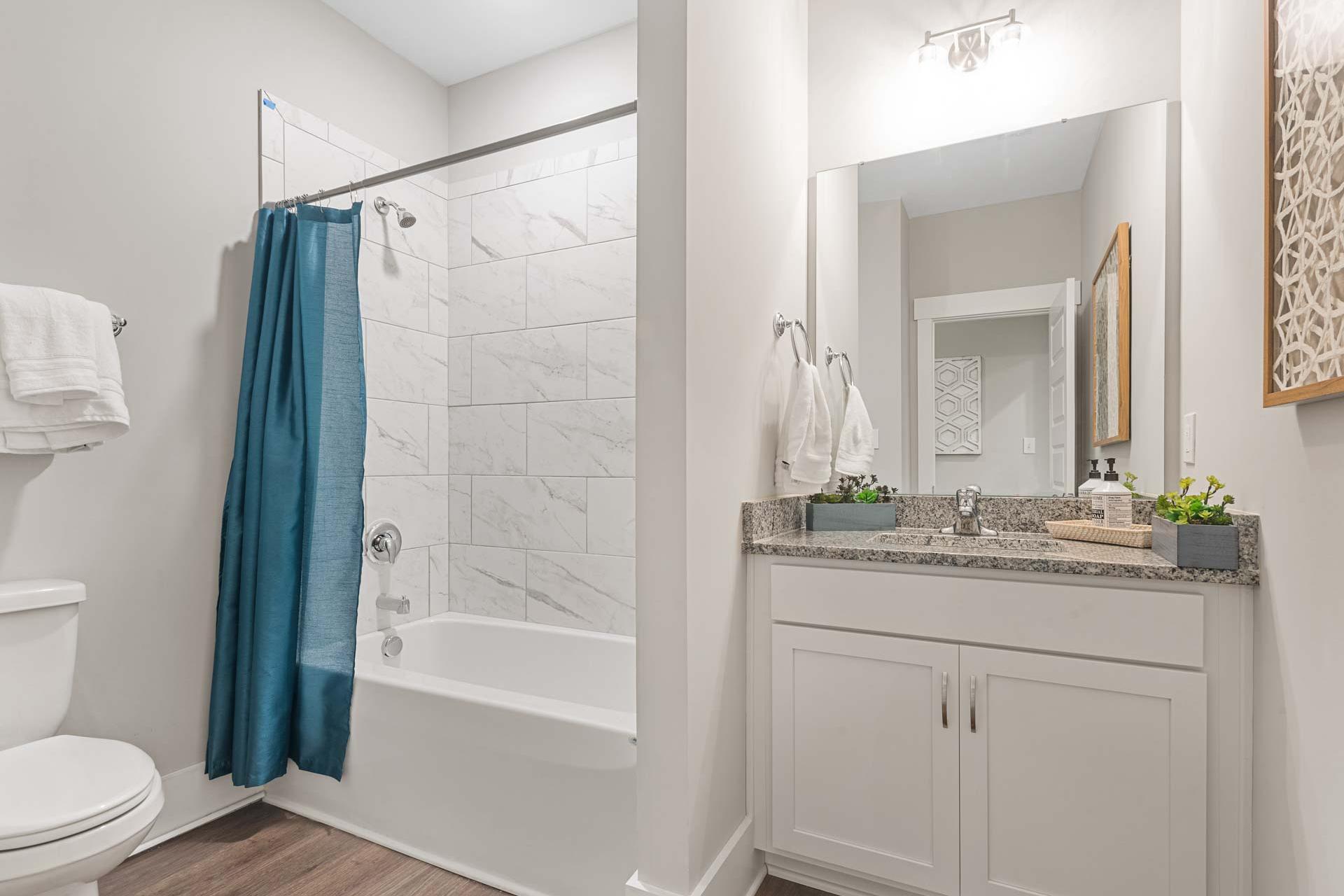 Spacious bathroom with teal shower curtain and bathtub at Monteagle Cove in Owens Cross Roads Alabama featuring white subway tile and double vanity