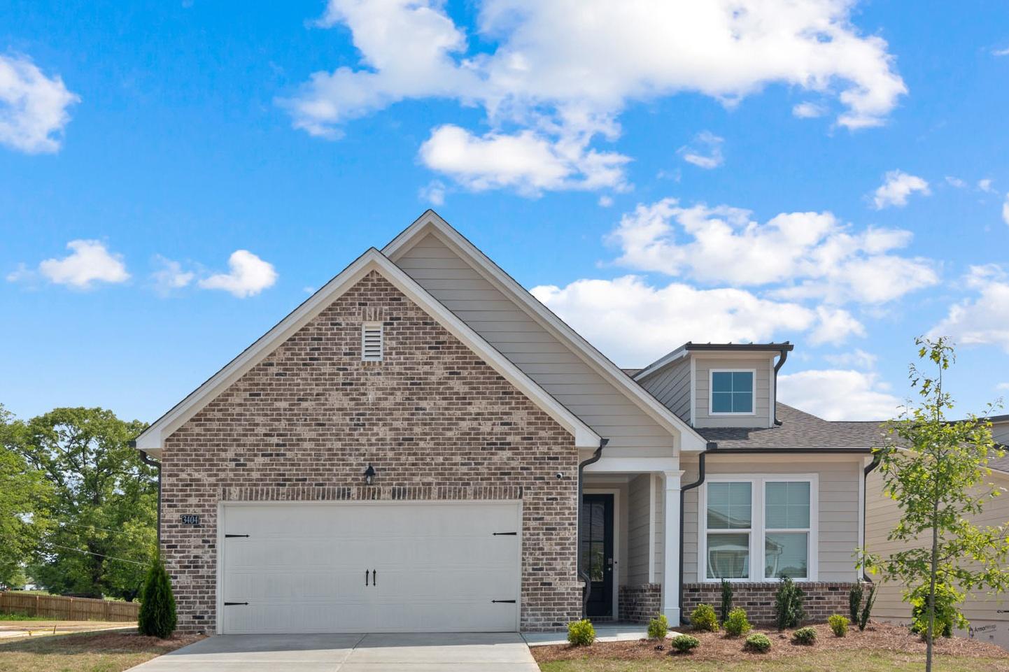 Glenwood C single-story home elevation at Wehunt Meadows showcasing brick and siding facade, 2-car garage, and front porch in Hoschton, GA