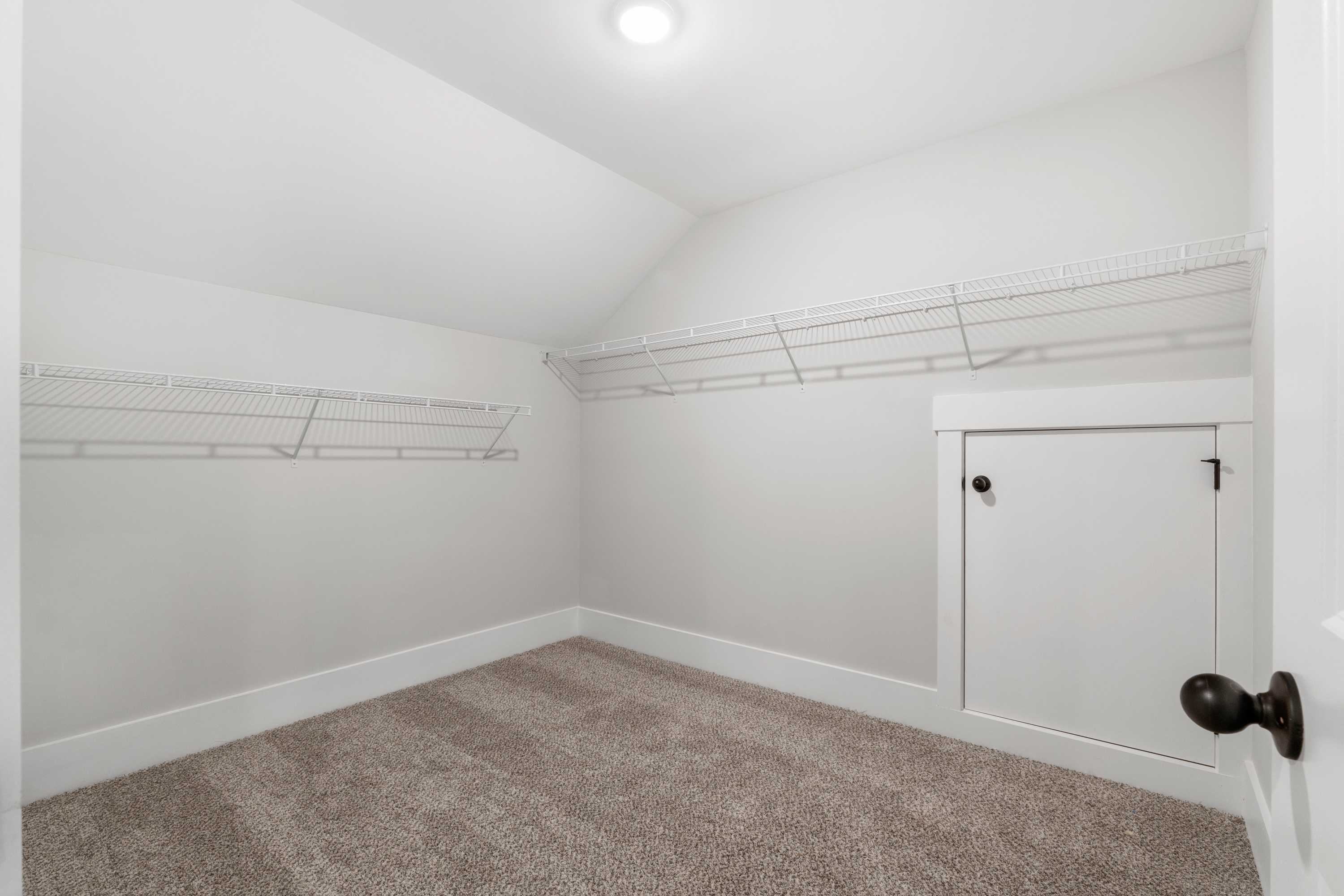 Spacious walk-in closet at Kendall Farms in Toney, Alabama with wire shelving, sloped ceiling, and carpeted floor