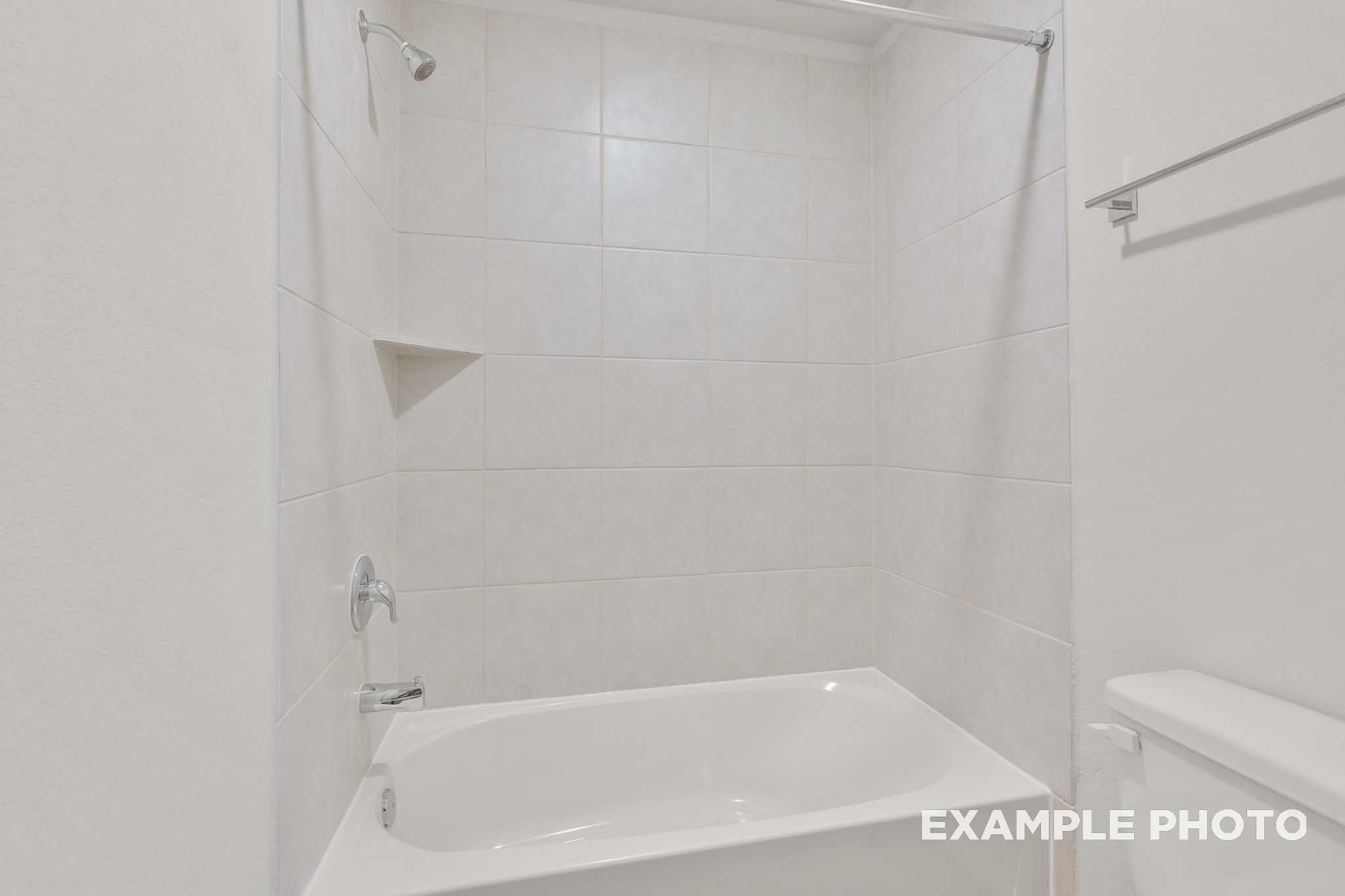 White tile shower and bathtub in the bathroom of The Brazos, a Davidson Homes single-family design in Beasley, Texas.