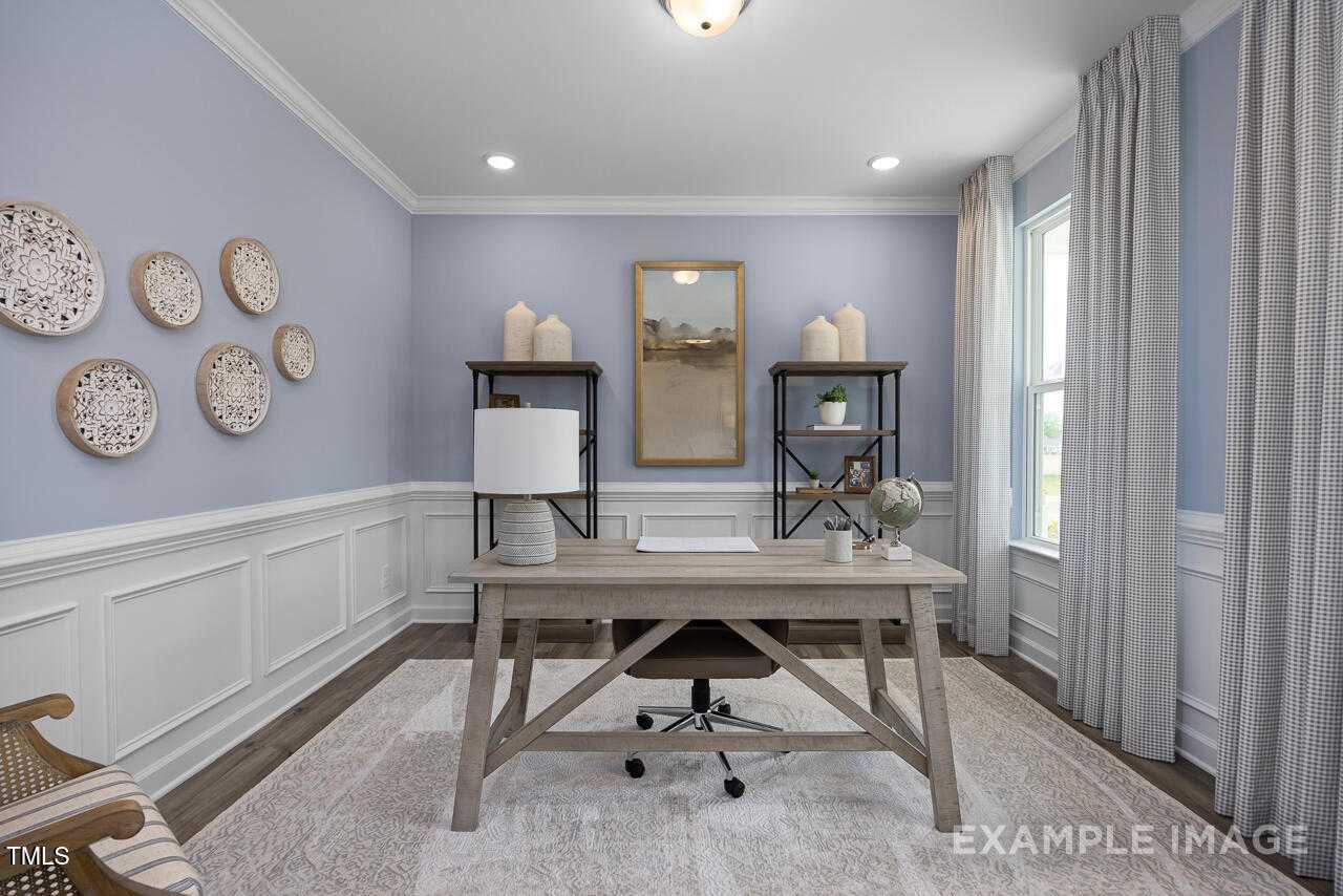 Cozy home office with rustic wooden desk, blue walls, woven decor, and bookshelf in Davidson Homes Magnolia B, Angier NC