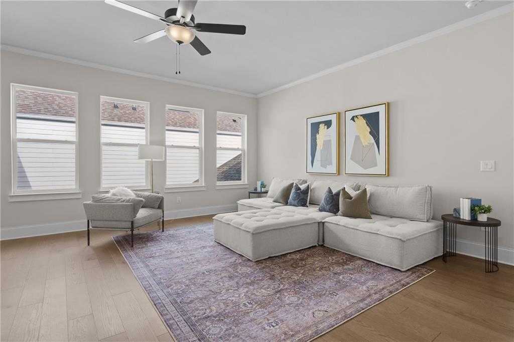 Cozy living room with gray L-shaped sectional sofa, ceiling fan, large windows, abstract art in Davidson Homes Seaside B, Woodstock GA