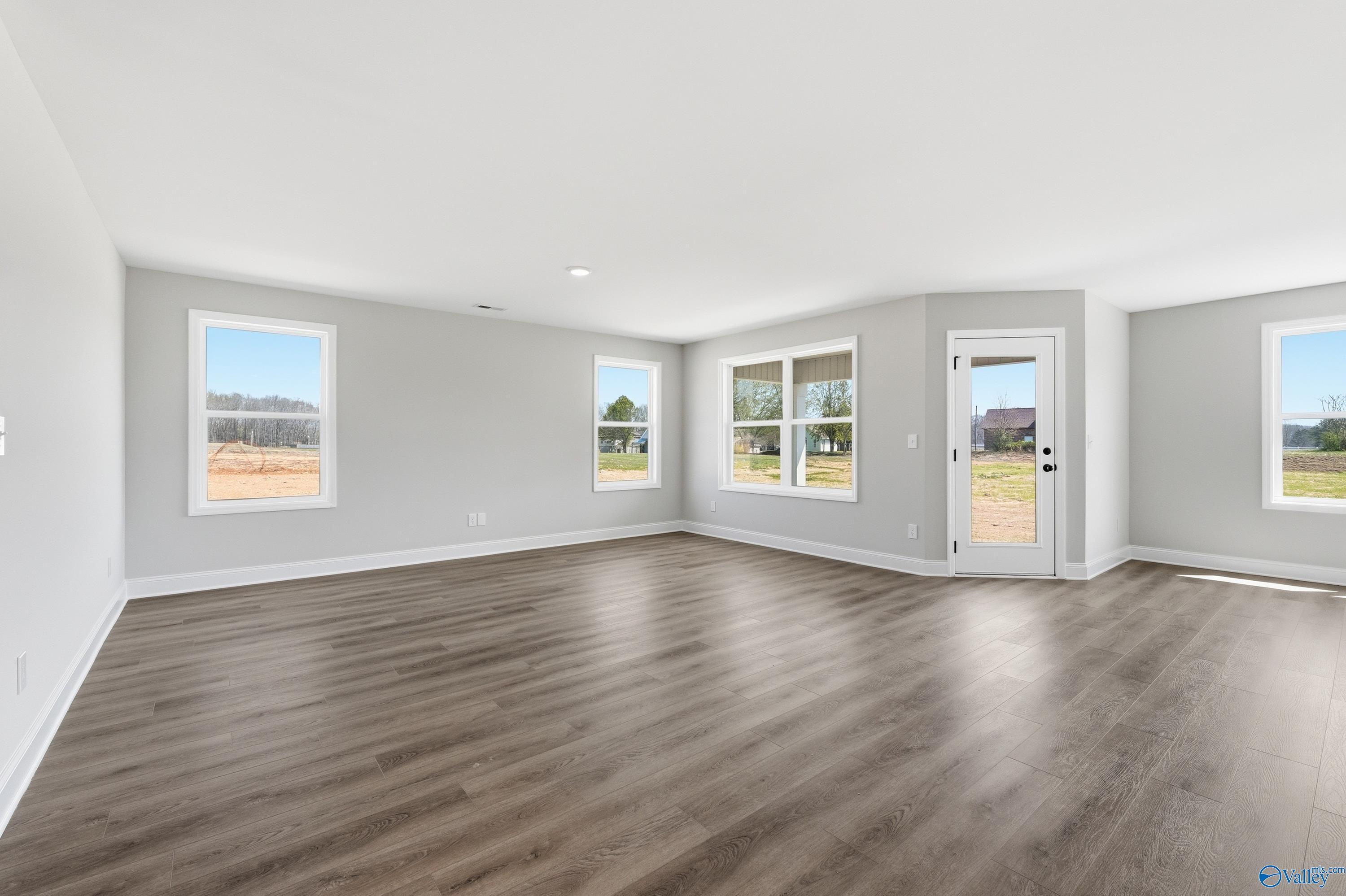 Spacious living room with hardwood floors, large windows, and gray walls in The Franklin V by Davidson Homes, Athens, Alabama